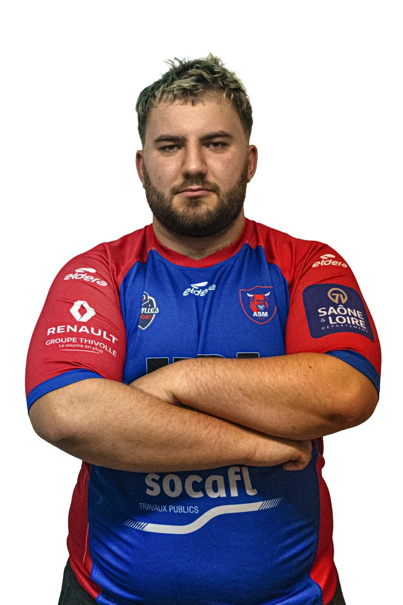 Jeune homme portant un maillot de rugby rouge et bleu, bras croisés, regard sérieux.