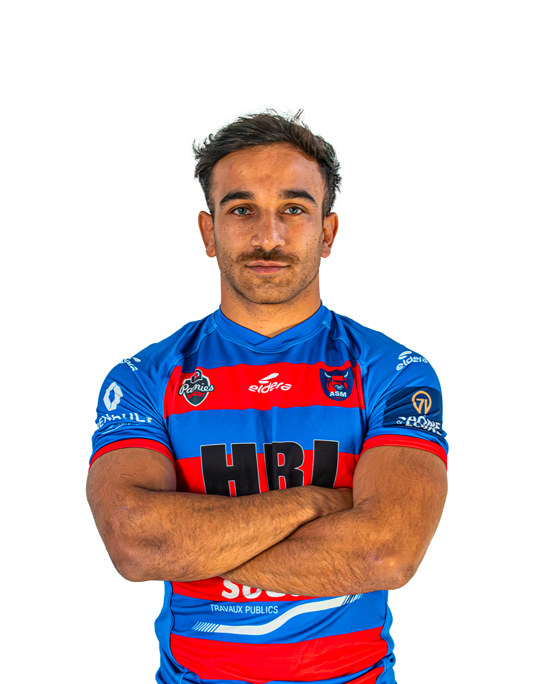 Un homme porte un maillot de rugby bleu avec des rayures rouges et une inscription HRI en gros caractères noirs, portant les bras croisés, debout contre un fond blanc.