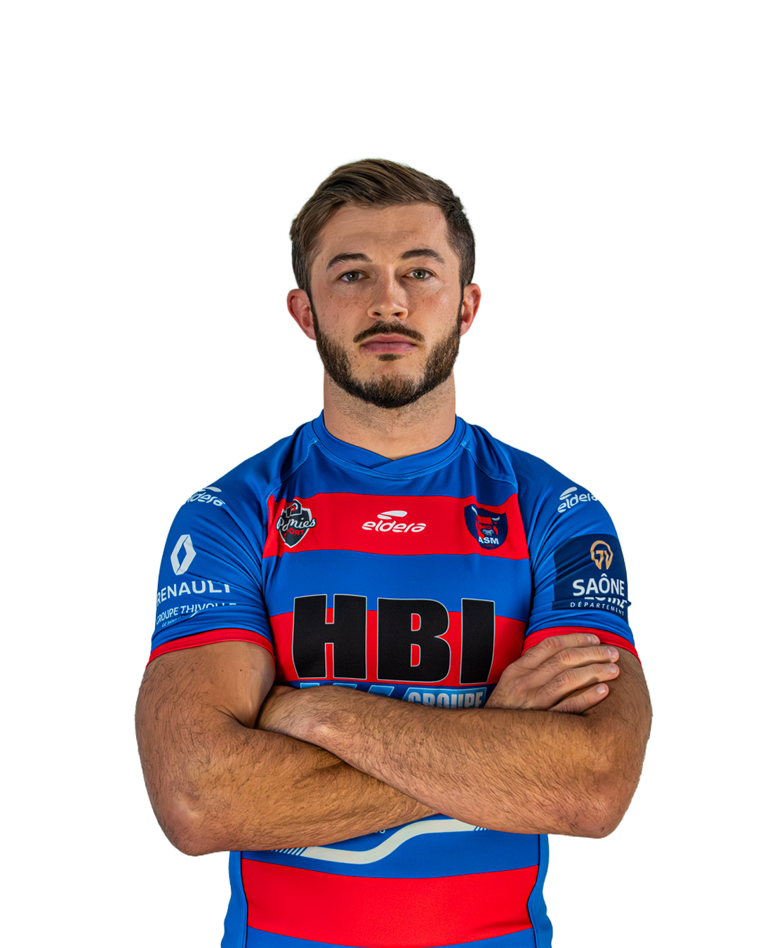 Un homme portant un maillot de rugby bleu, rouge et noir avec des logos, croisant les bras, regardant droit avec une expression sérieuse.
