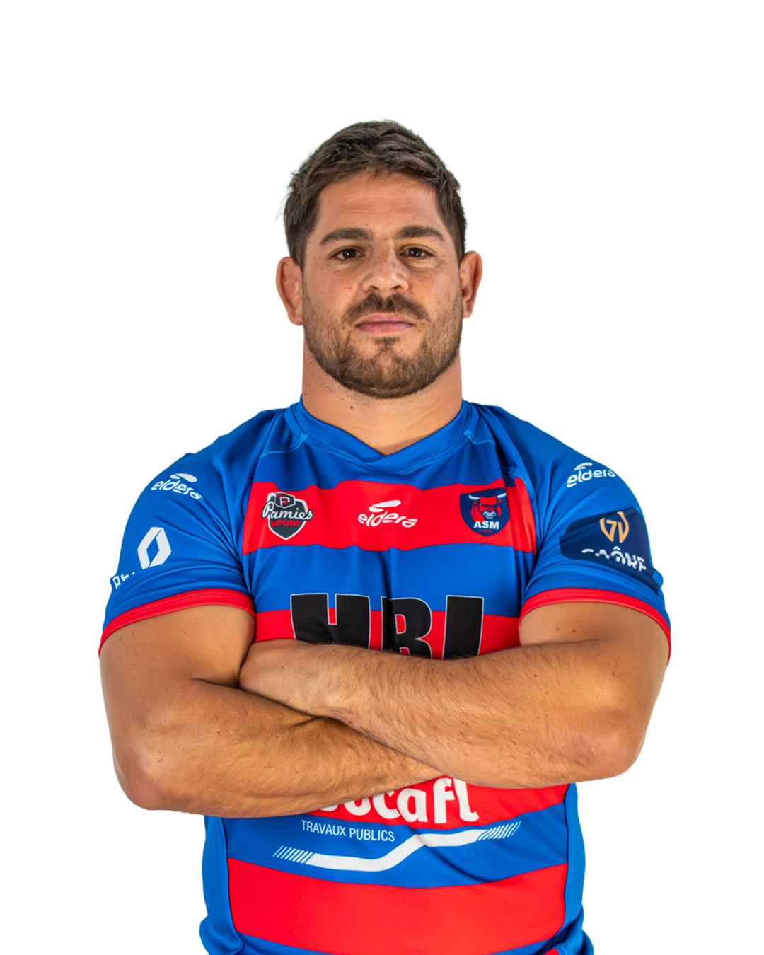 Un homme avec une barbe portant un maillot de rugby bleu avec des rayures rouges et noires, posé avec les bras croisés. Le maillot comporte plusieurs logos, dont ceux d'une équipe de rugby.