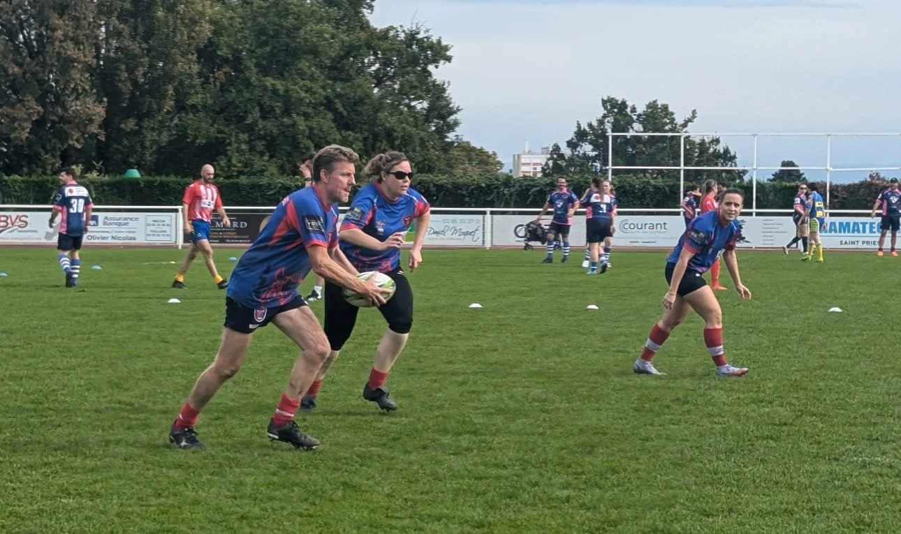 Des personnes jouent au rugby sur un terrain vert, certaines en train de courir avec le ballon, d'autres en position bêach ou en préparation.