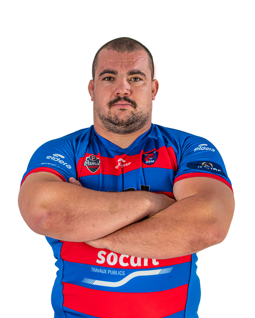 Un homme portant un maillot de sport bleu, rouge avec des logos, les bras croisés, regardant droit devant.