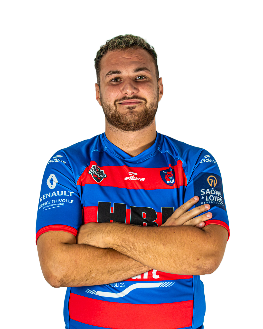 Un homme portant un maillot de football bleu avec des bandes rouges, croisant les bras, regardant vers l'avant, souriant légèrement.