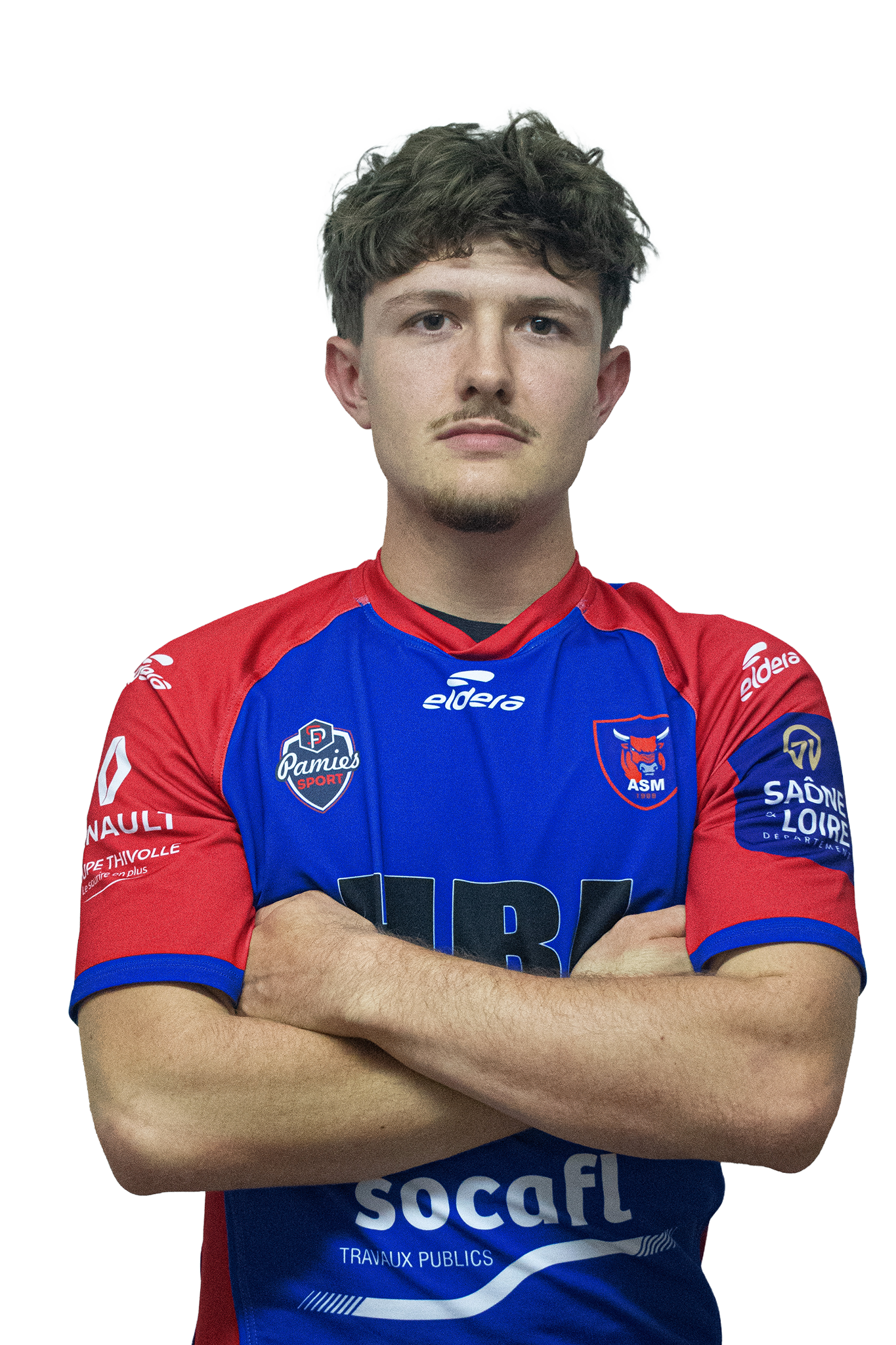 Un jeune homme en maillot de sport bleu et rouge avec des logos de sponsors et un blason de rugby, bras croisés, regardant devant lui.