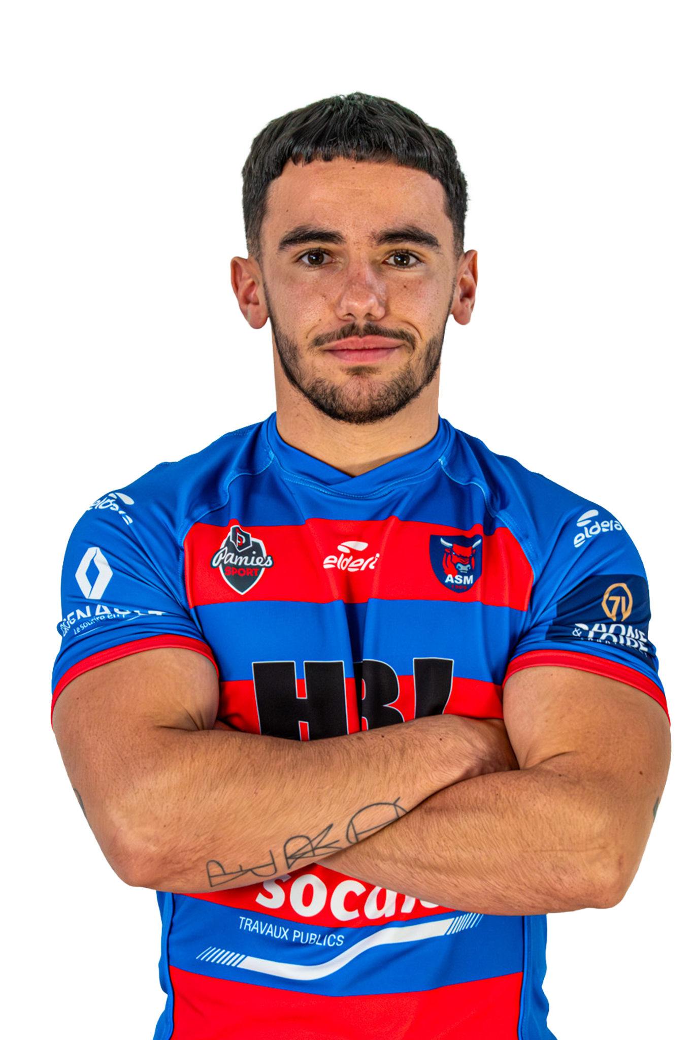 Un joueur de rugby portant un maillot bleu avec des bandes rouges et noires, les bras croisés, regardant vers l'avant.