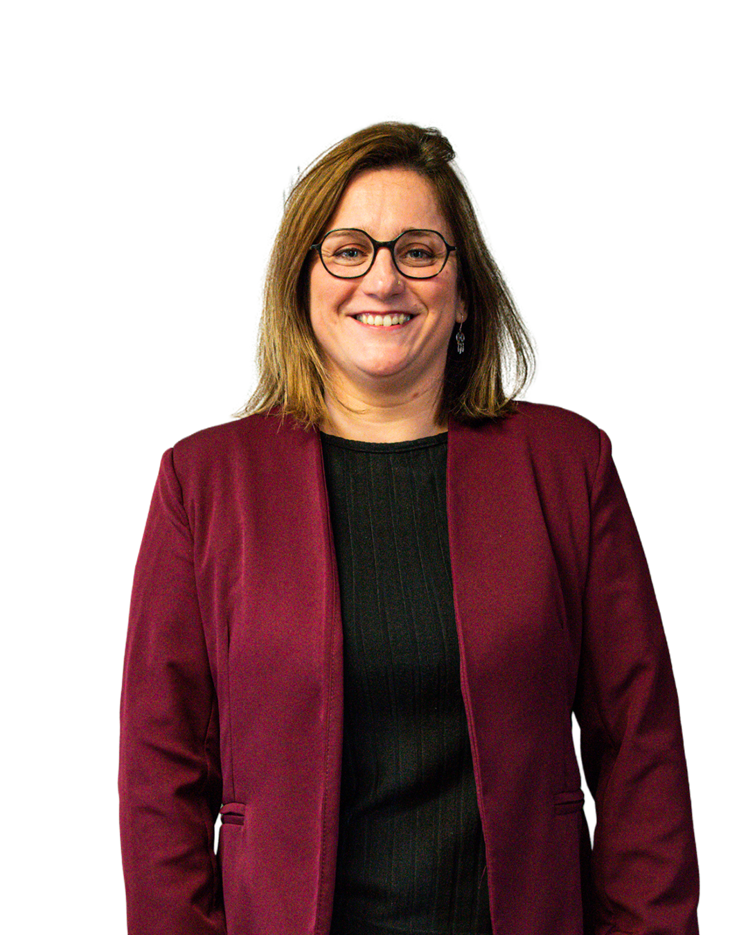 Une femme souriante portant des lunettes, un blazer marron foncé et un haut noir, posant contre un fond dégradé.