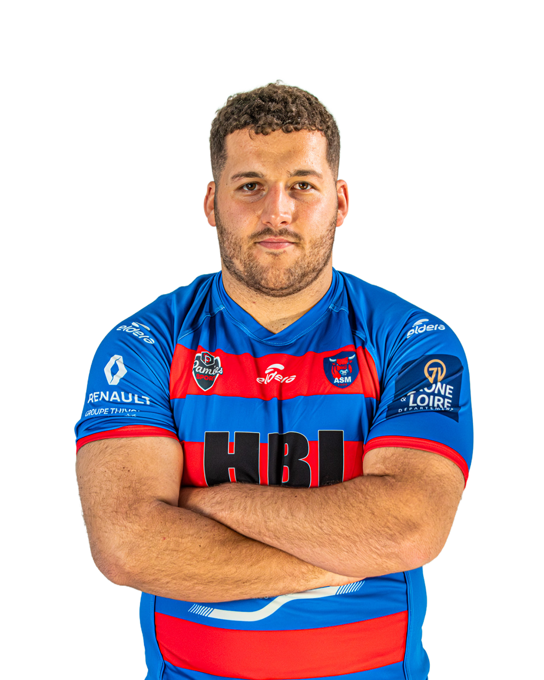 Un homme portant un maillot de rugby bleu et rouge avec ses bras croisés pose pour une photo.