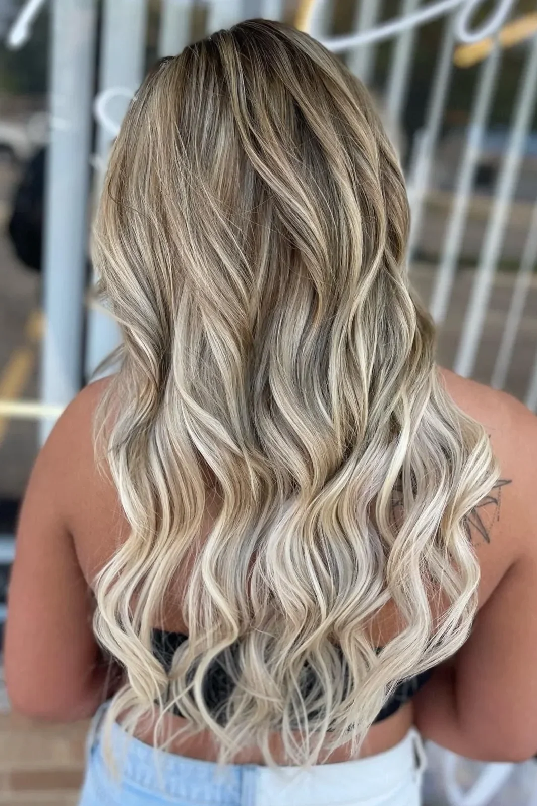 Back view of a woman with long, wavy blonde hair.