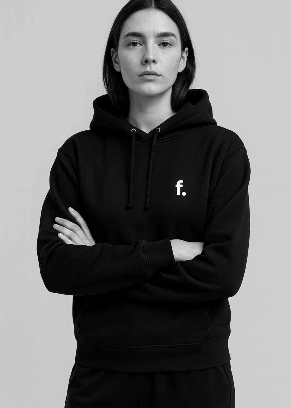 A young woman with dark hair wearing a black hoodie with a small white letter "f" on the chest, standing with arms crossed against a plain light background.