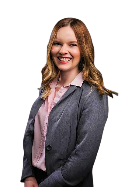 A woman with long, wavy red hair wearing a gray blazer over a pink blouse, smiling and posing against a black background.