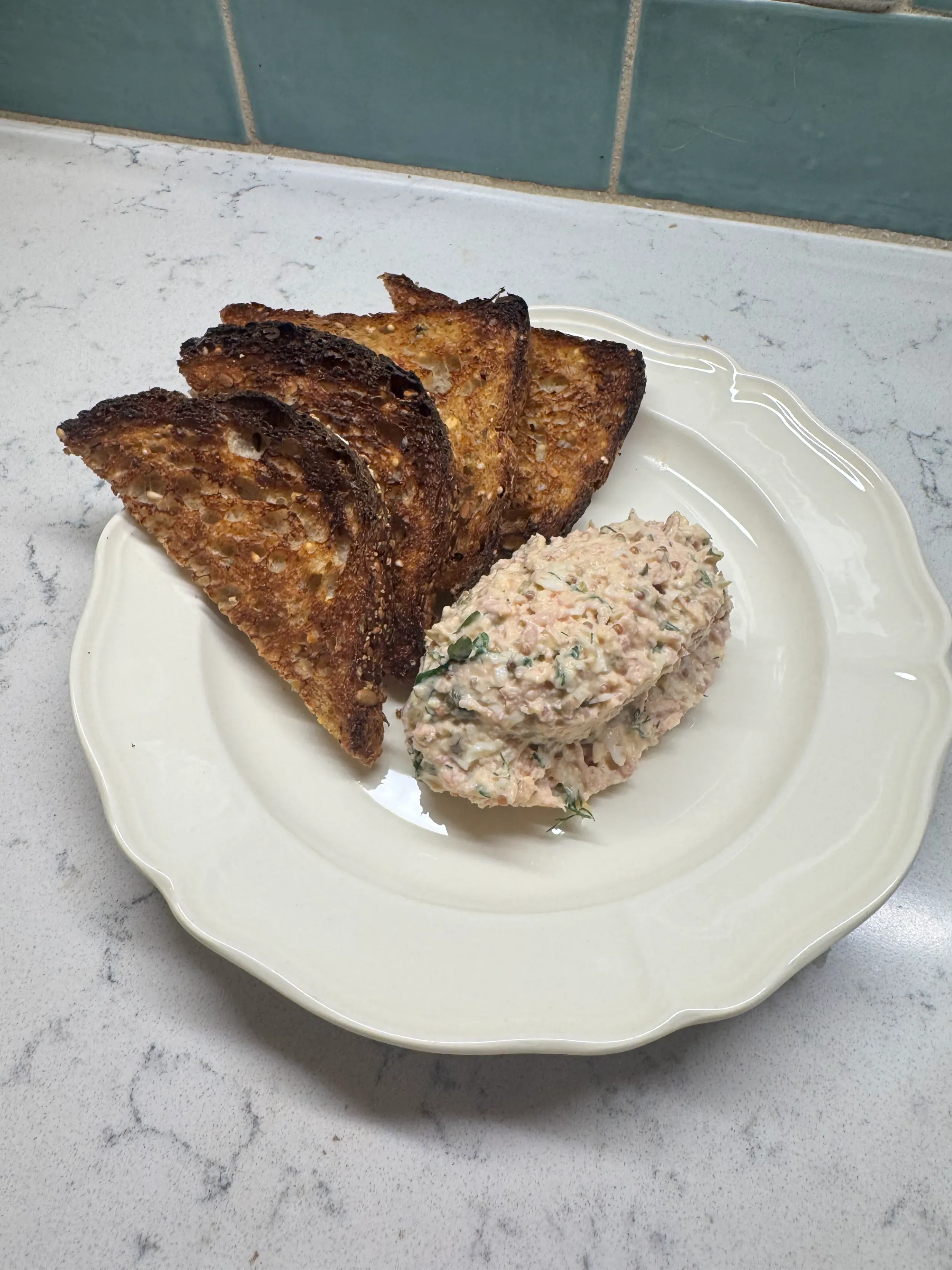 A plate of French toast and a serving of tuna salad on a white decorative plate