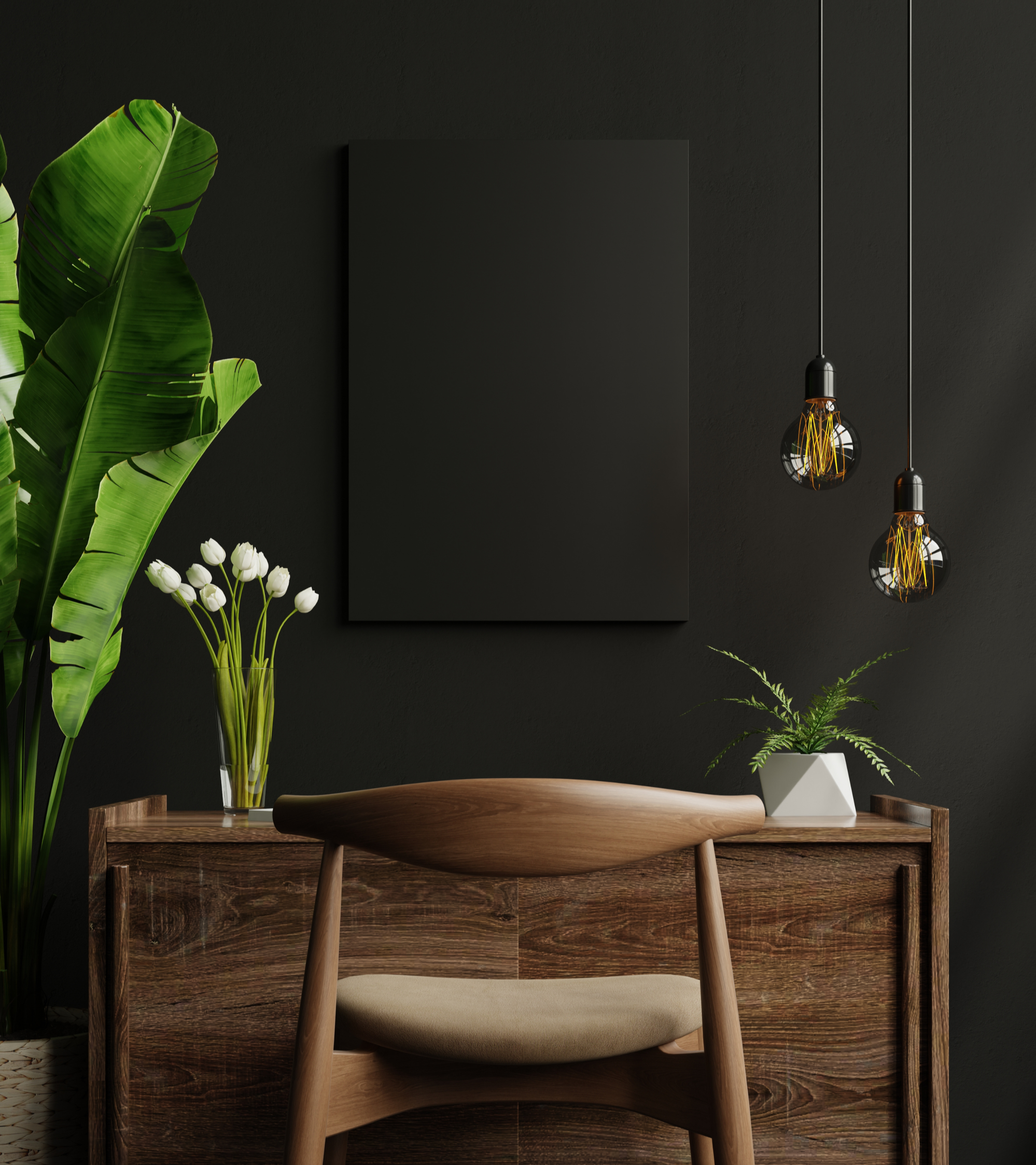 Minimalist home office with a wooden desk, beige chair, tall green plants, white flowers in a glass vase, black wall, black canvas, and two hanging Edison-style light bulbs.