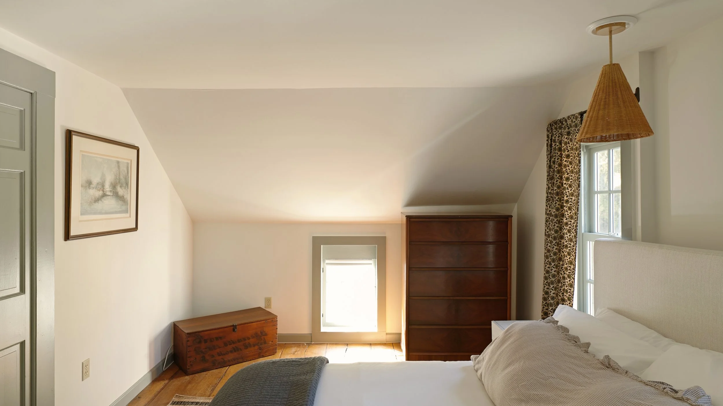 Bedroom with a bed, dresser, small window, and a framed painting on the wall.