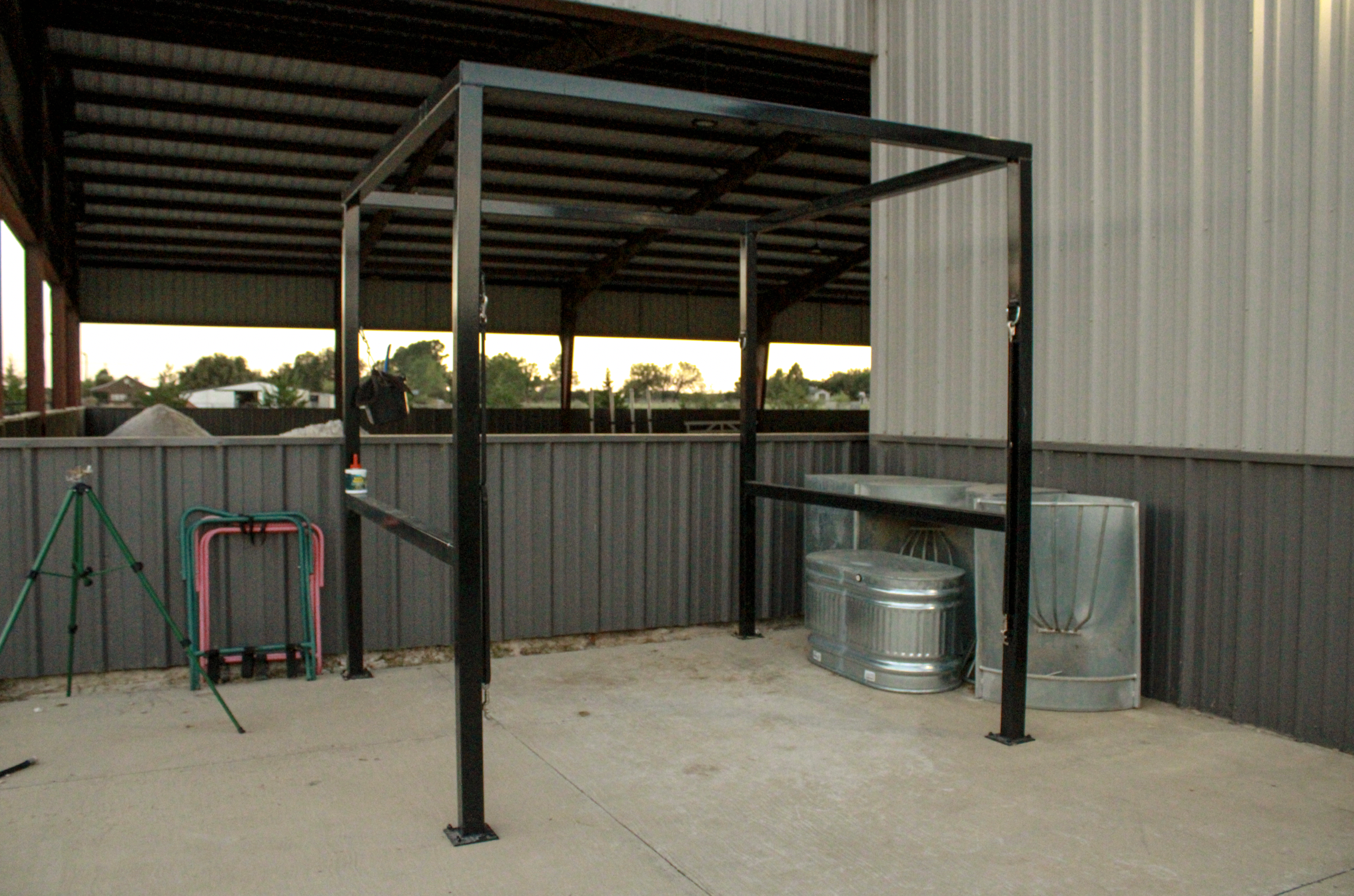 Metal wash rack, beige and gray metal wall behind an outdoor covered area at sunset.
