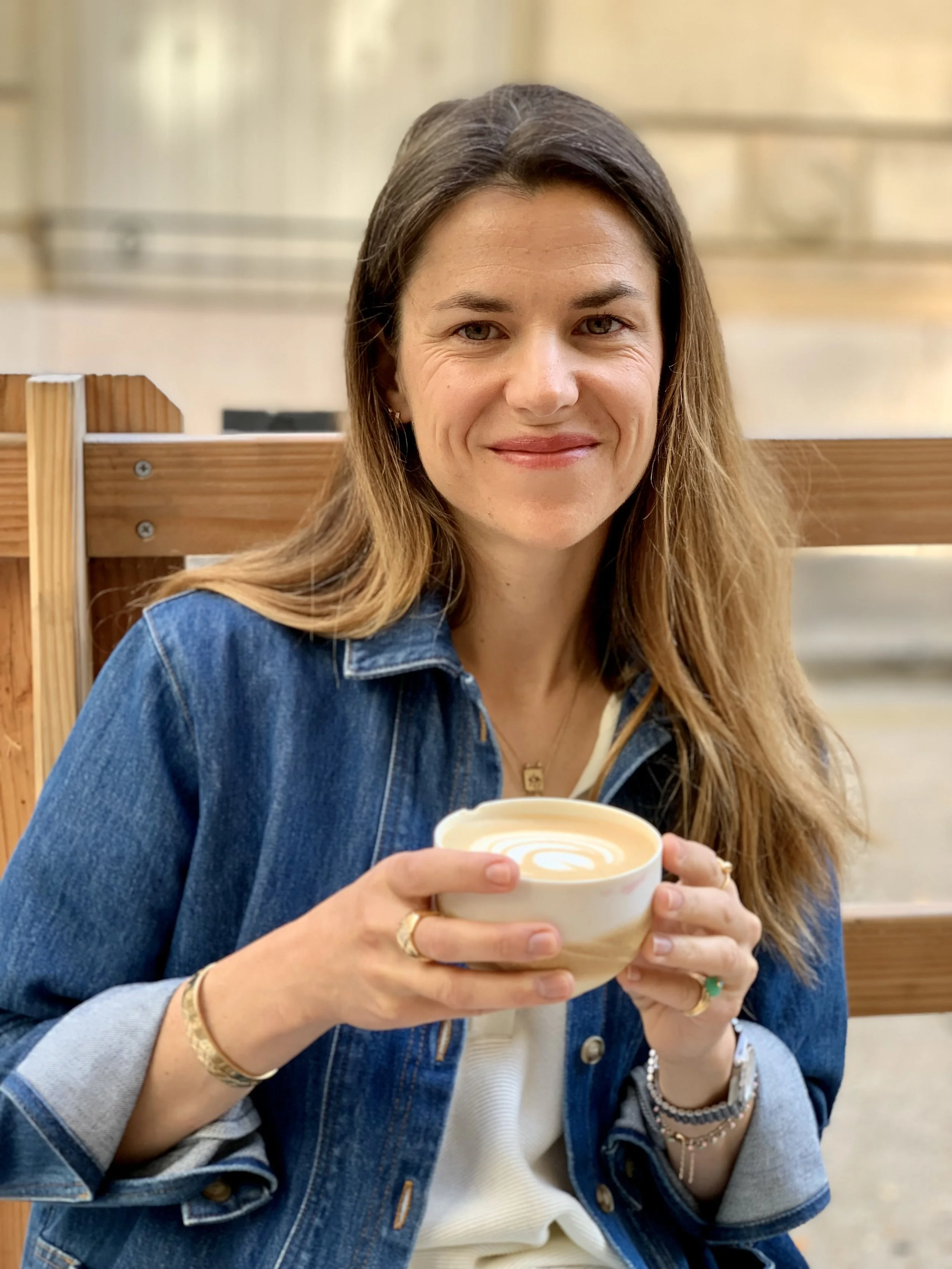 Une femme souriante tenant une tasse de café.