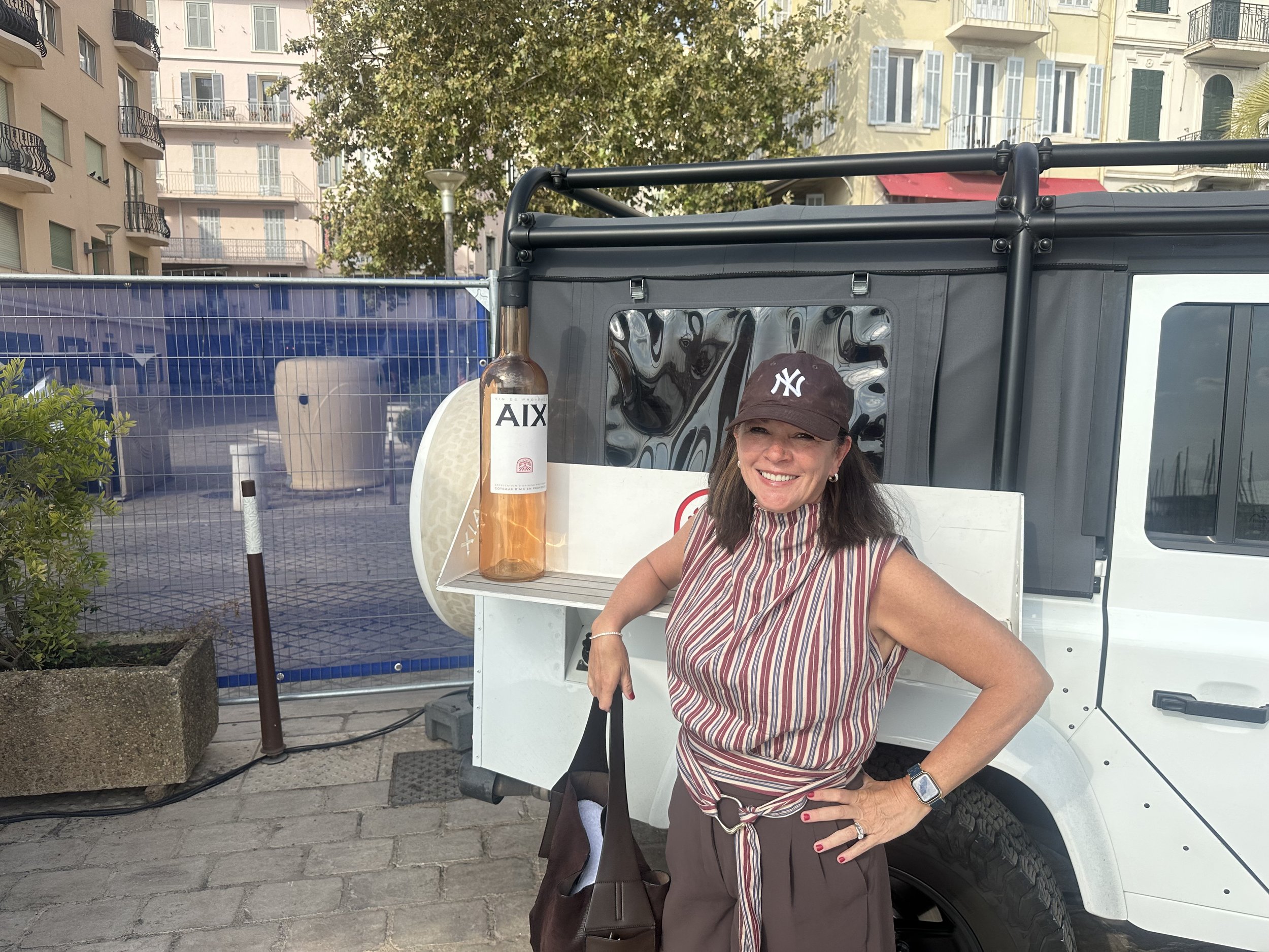 Woman smiling next to a giant AIX rosé bottle display on the Vieux-Port in Cannes, France