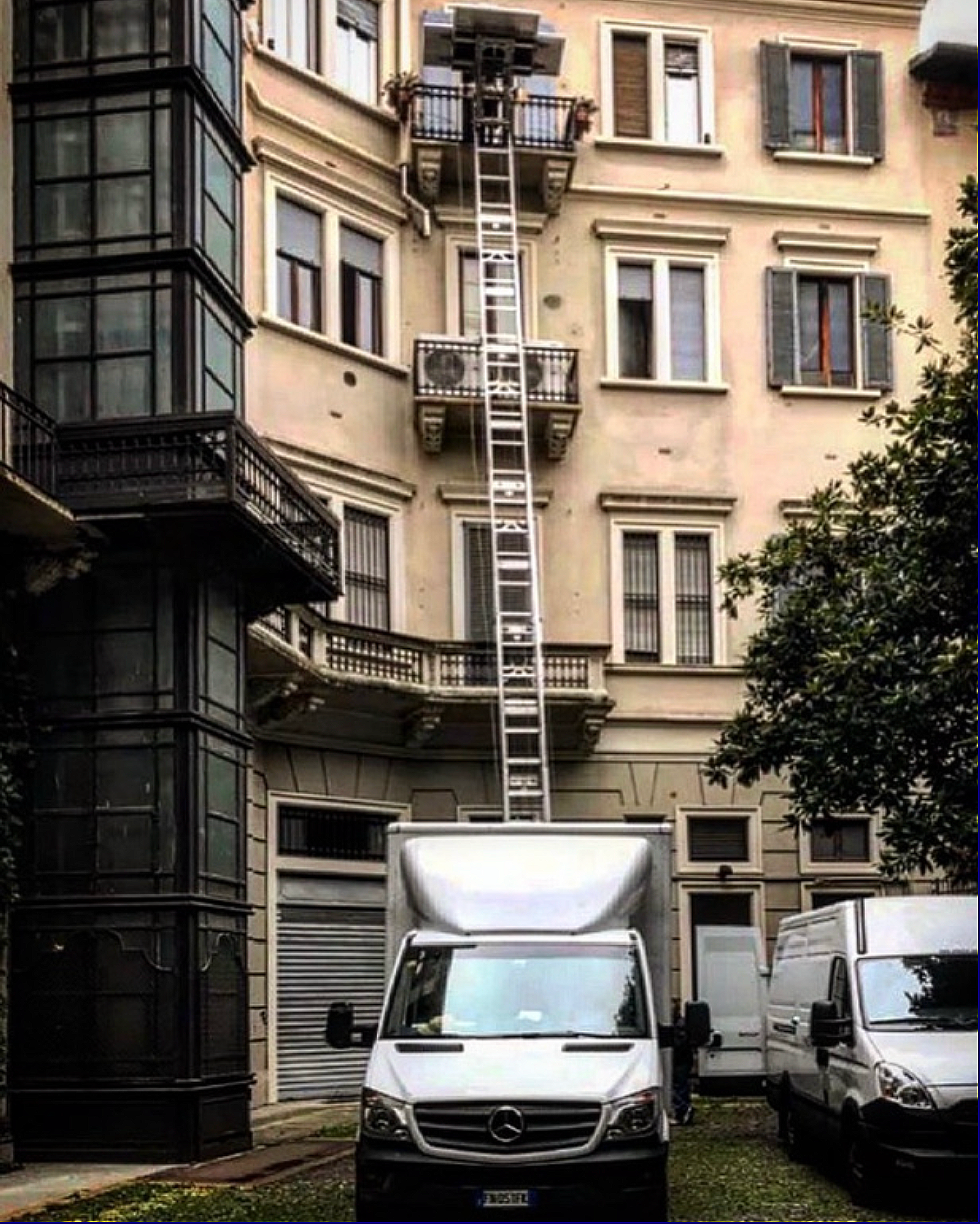 Furgone Mercedes parcheggiato davanti a un edificio, dove si vede un carro attrezzi con un'Altra vettura, con una scala lunga che arriva fino a un balcone.
