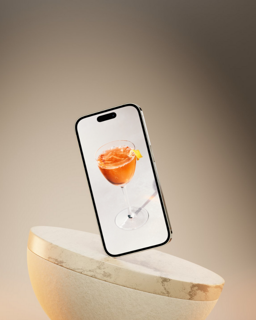 Smartphone on a white stand displaying a photo of a cocktail with an orange slice garnish.