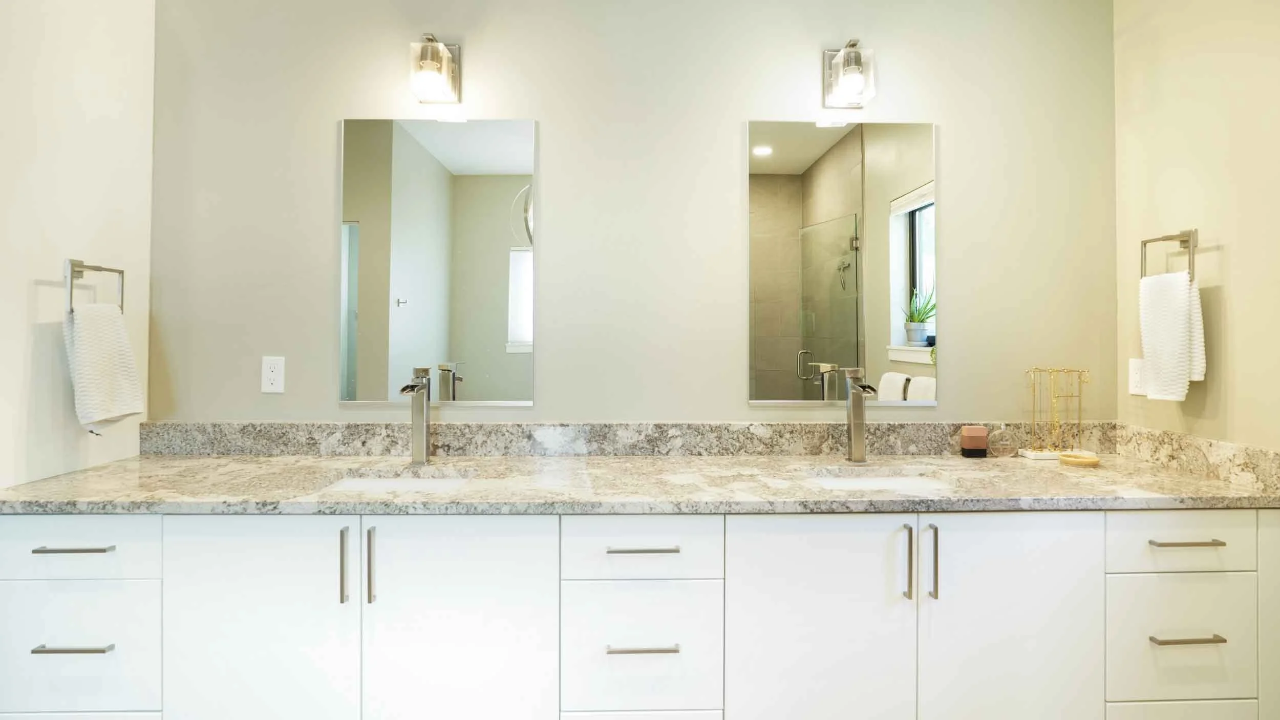 A double bathroom vanity with granite countertop, two sinks, two mirrors, and two wall-mounted lights built by home contractors durango