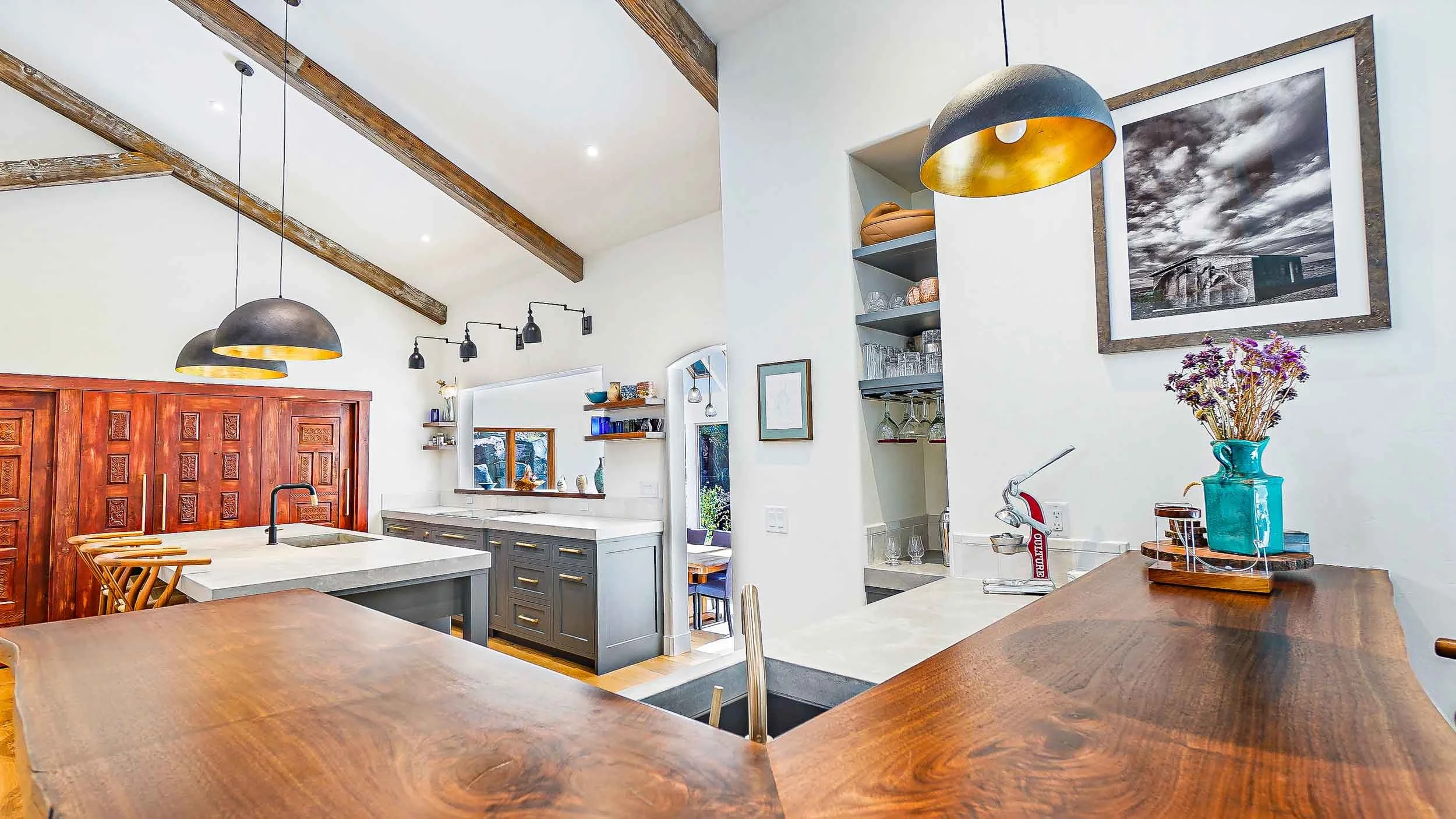Modern kitchen with a large wooden counter, white walls, and exposed wooden beams on the ceiling designed and built by Taylor builders who are remodeling contractors in durango