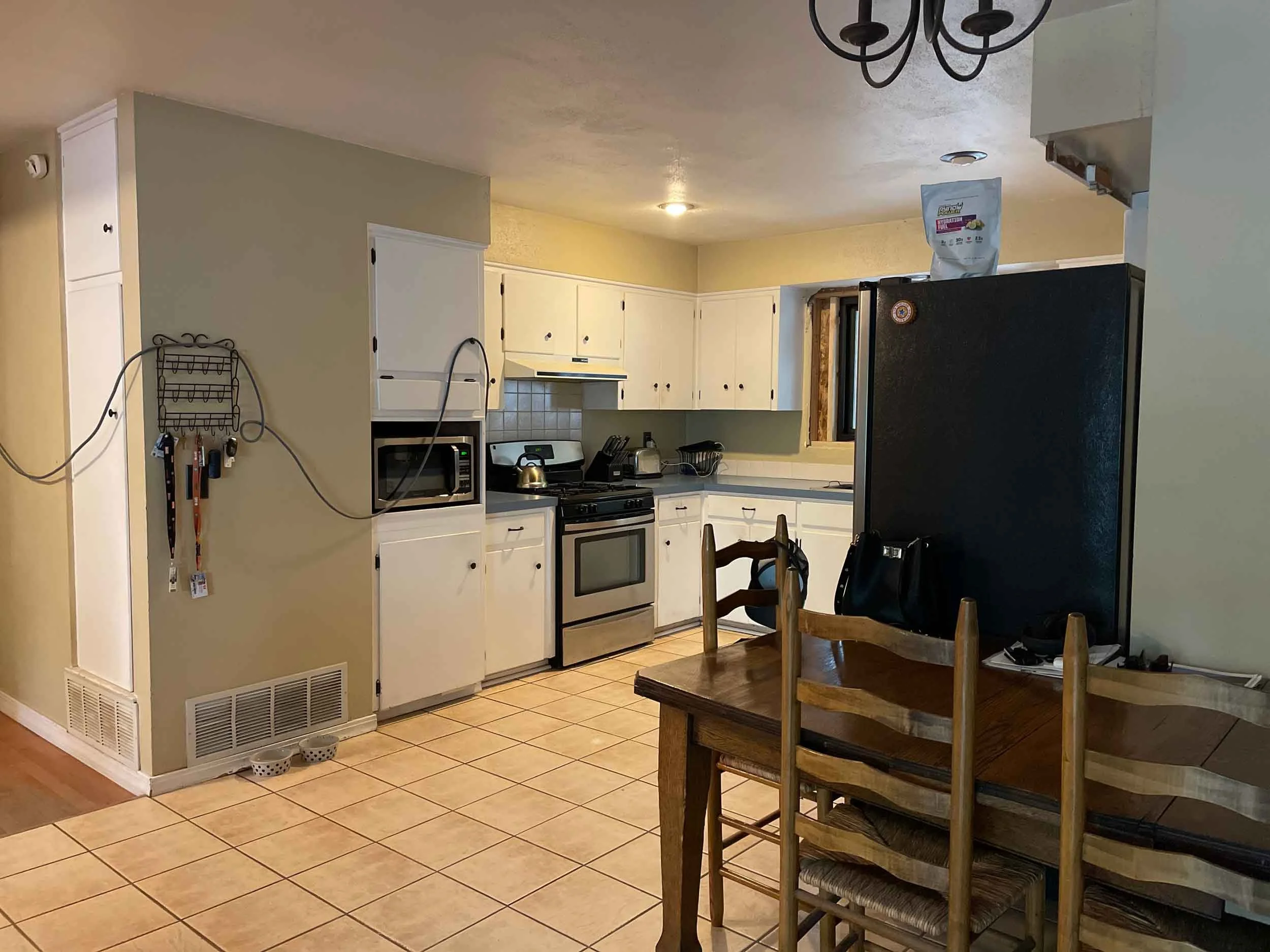 Kitchen with white cabinets, stove, microwave, refrigerator, and dining table with chairs built by durango colorado home builders