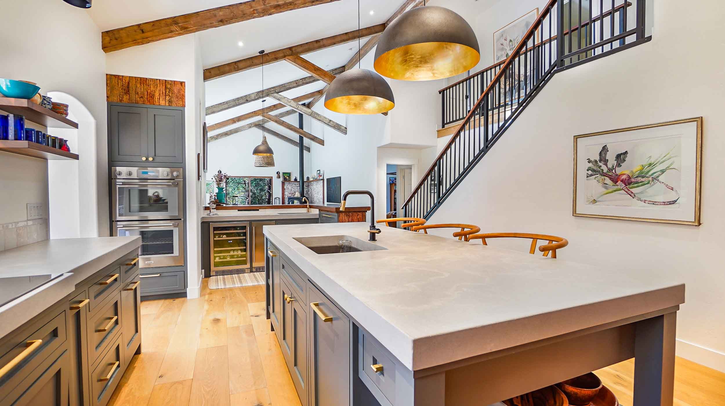 Modern kitchen with gray cabinetry, a large island with a white countertop, pendant lights, and wood flooring built by general contractors durango co