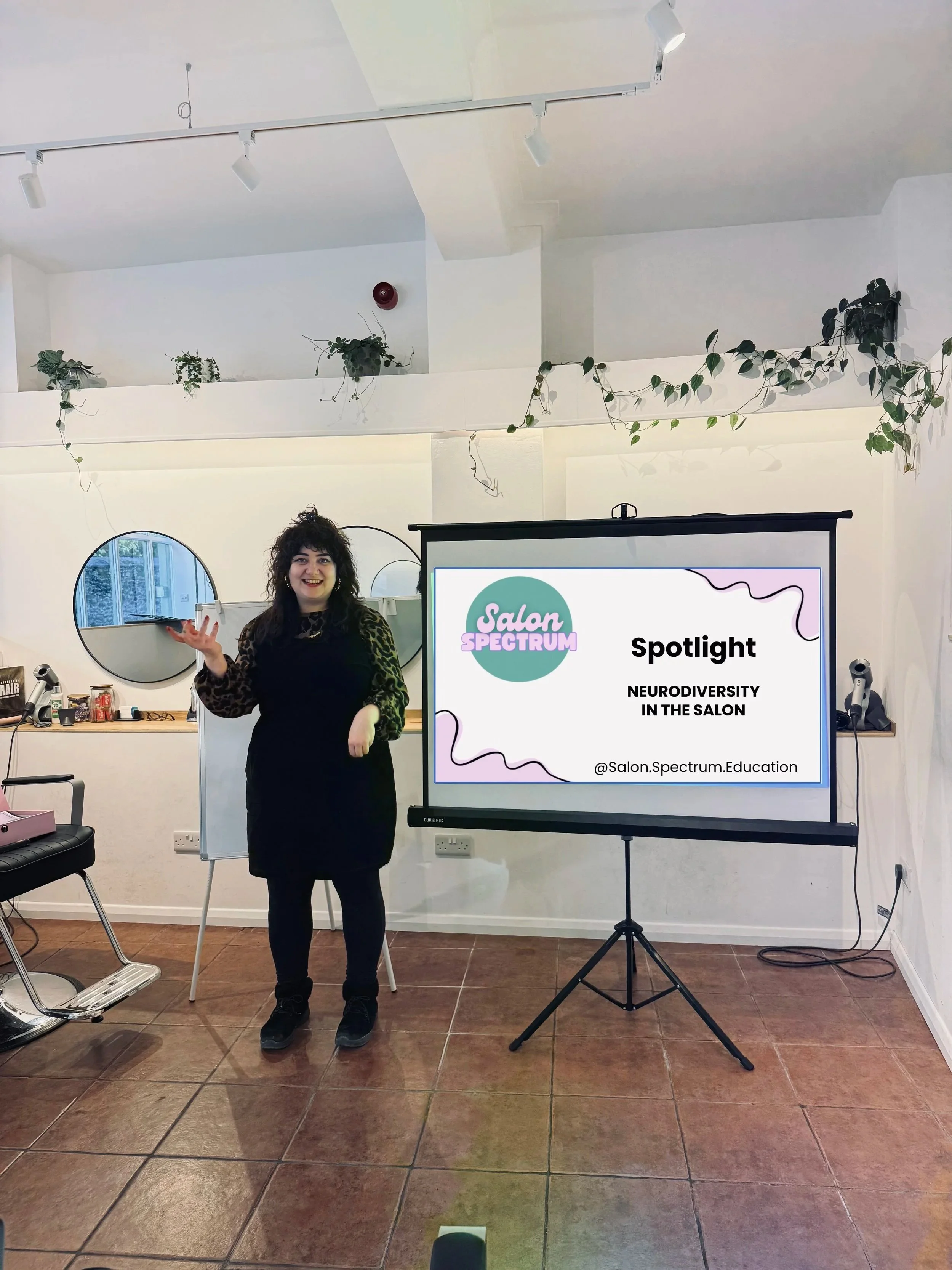 hairdresser at front of salon teaching salon spectrum course about neurodiversity.