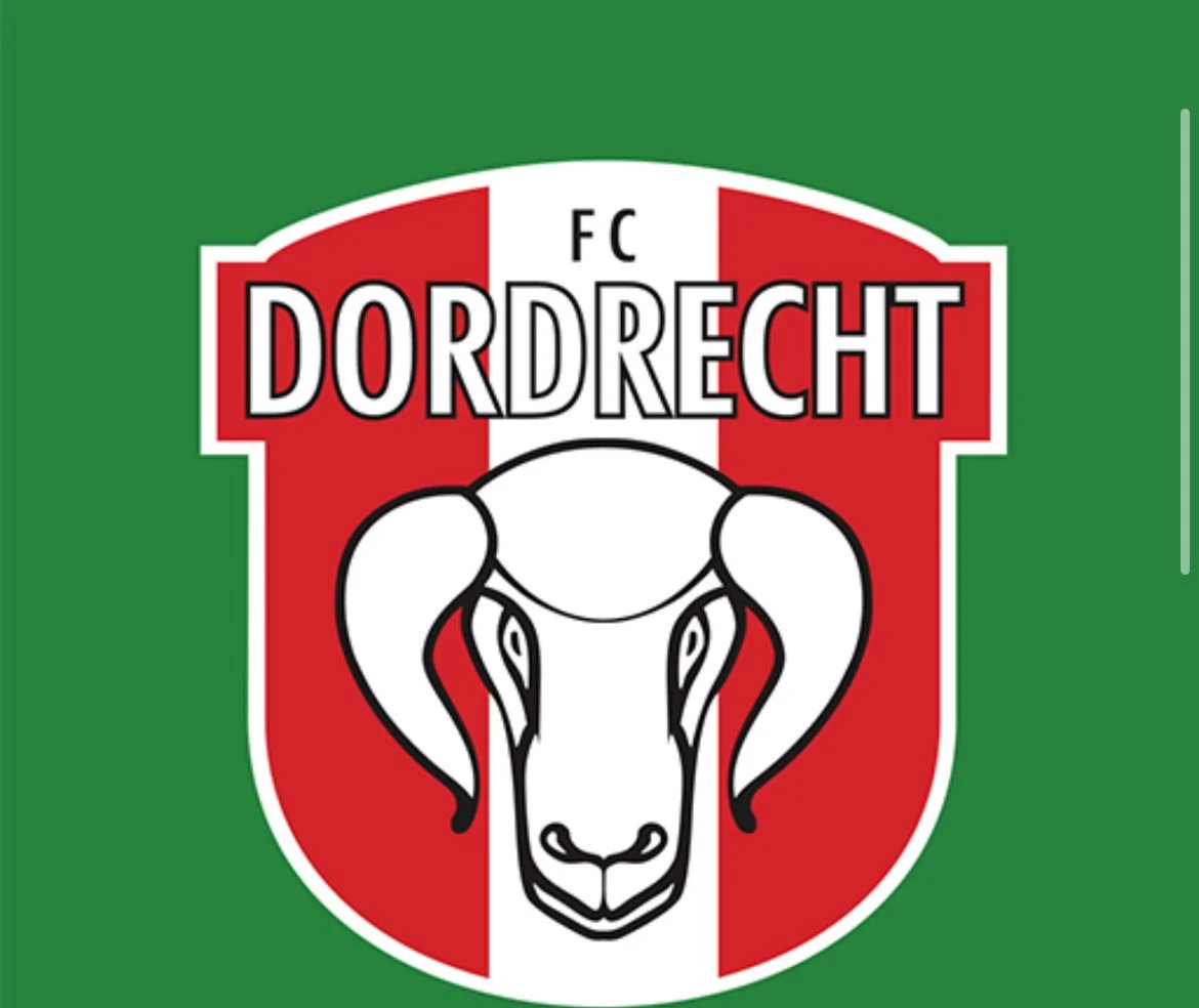 Logo of FC Dordrecht featuring a ram's head, with red, white, and green colors.