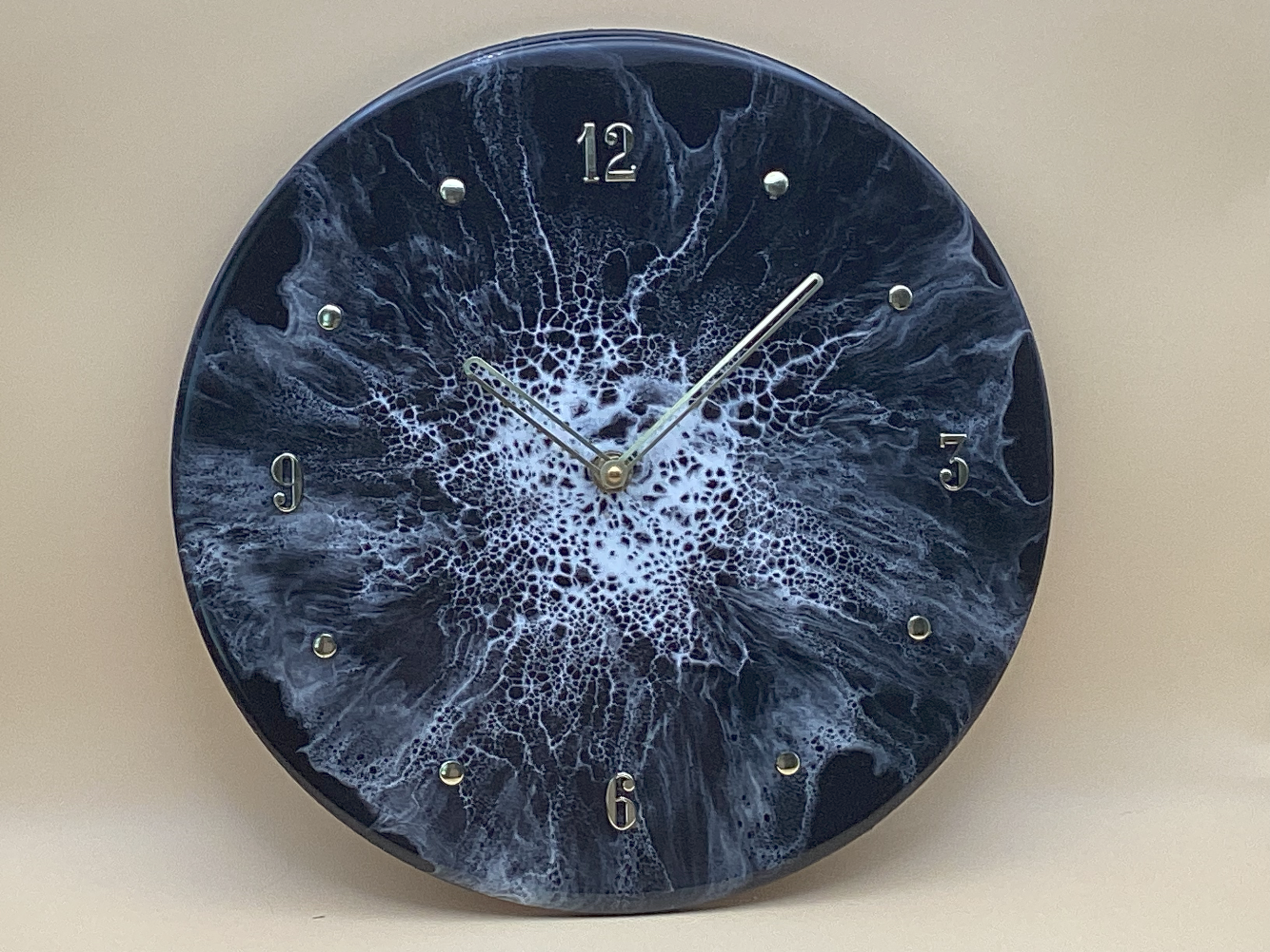 Wall clock with a dark blue/black face featuring white and blue marble-like patterns and silver numbers at 12, 3, 6, and 9, with silver hour, minute, and second hands.