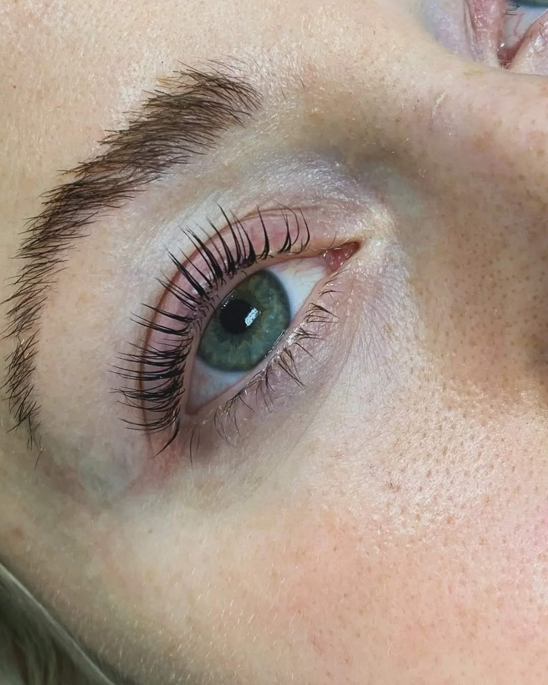 Close-up of an eye showing lifted, curled natural lashes after a lash lift service.