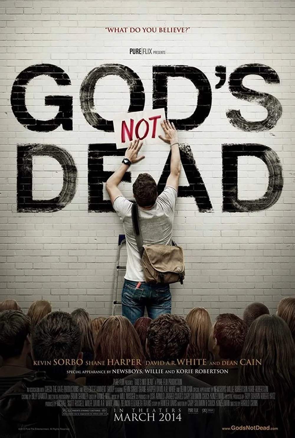 Movie poster for 'God's Not Dead' featuring a person hanging a sign that says 'NOT' on a wall that reads 'GOD'S DEAD' with an audience at the bottom and the release date March 2014.