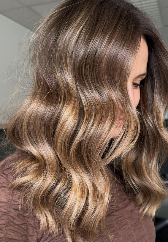Cheveux longs, ondulés, et bruns avec des reflets dorés sur une femme