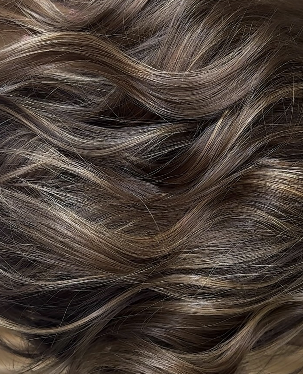 Cheveux longs et ondulés de couleur brun clair avec des reflets.