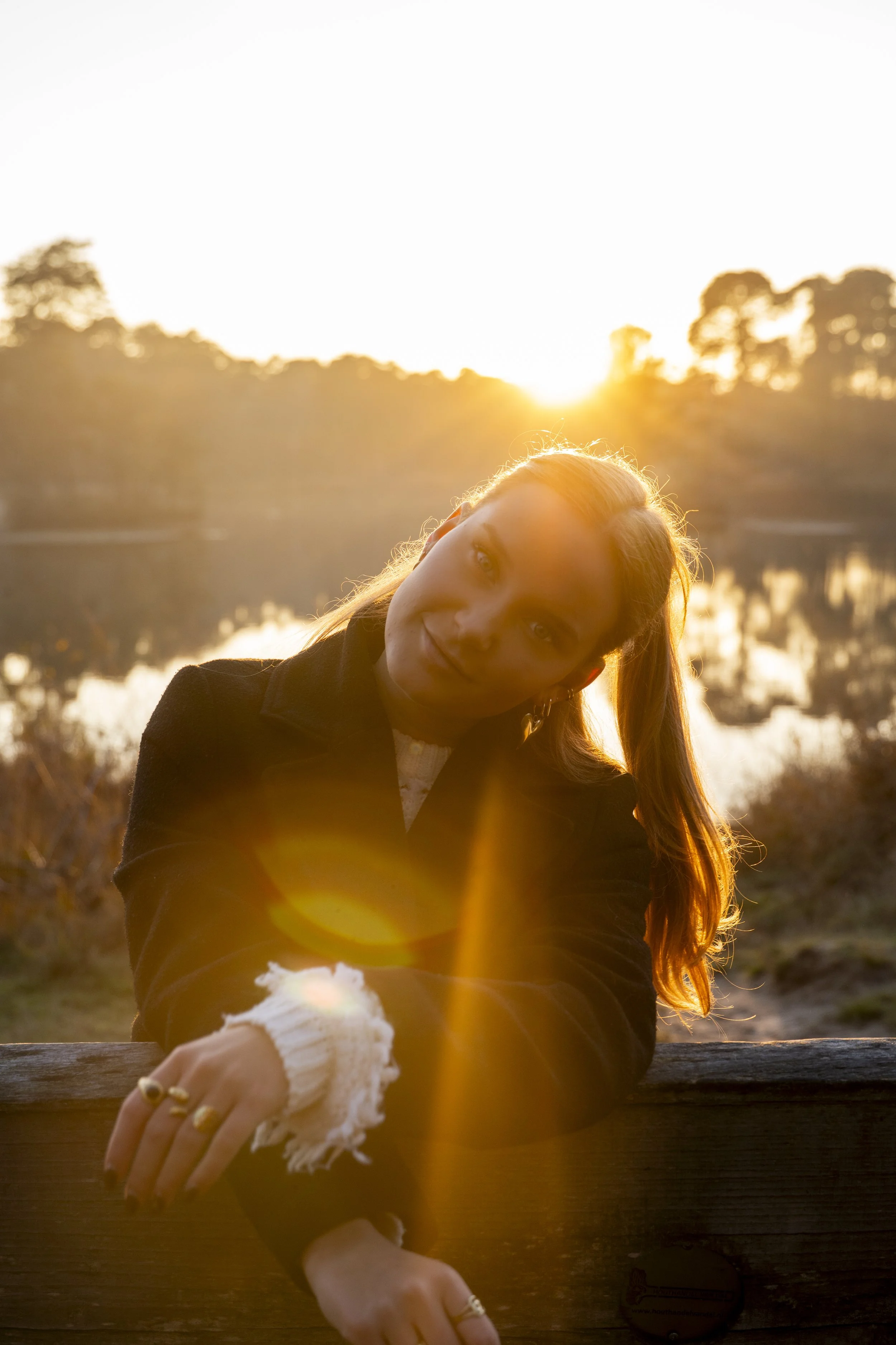 Vrouw die ontspant bij een meer bij zonsondergang, het licht van de zon schijnt door haar haar.