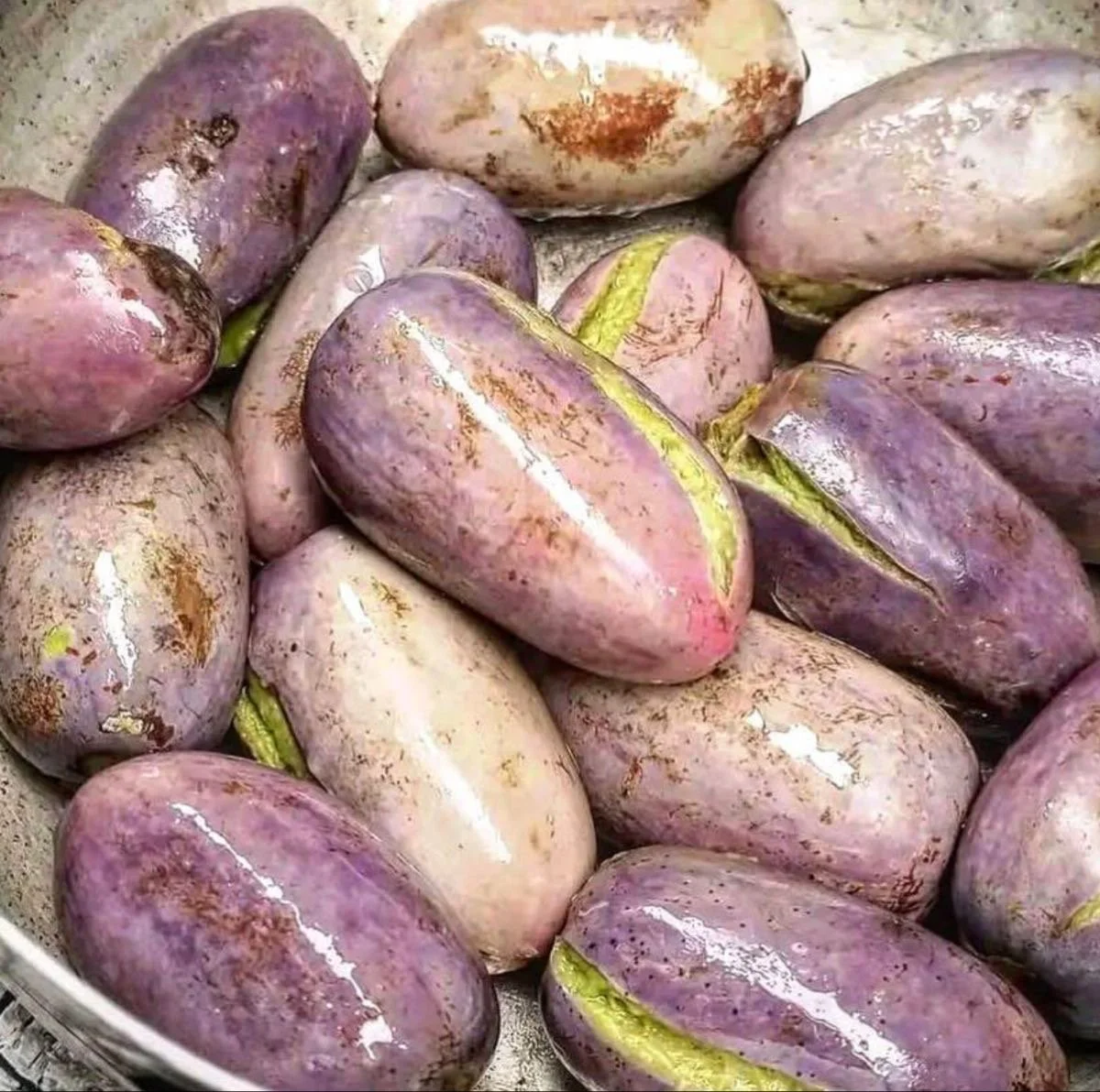 Pommes de terre violettes avec une peau sale et quelques tiges vertes.
