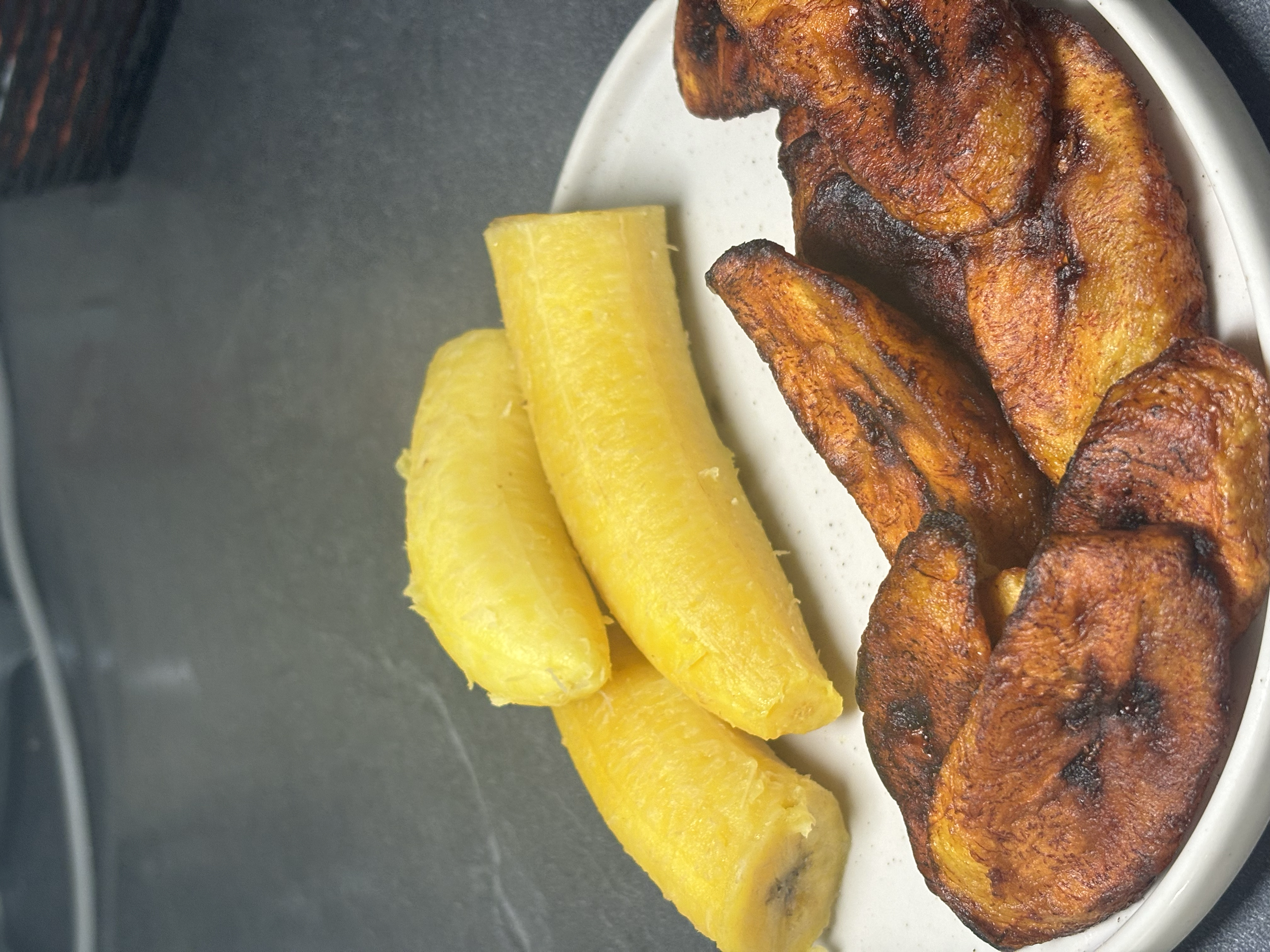 Bananes plantains frits et un morceau de poulet frit sur une assiette blanche.