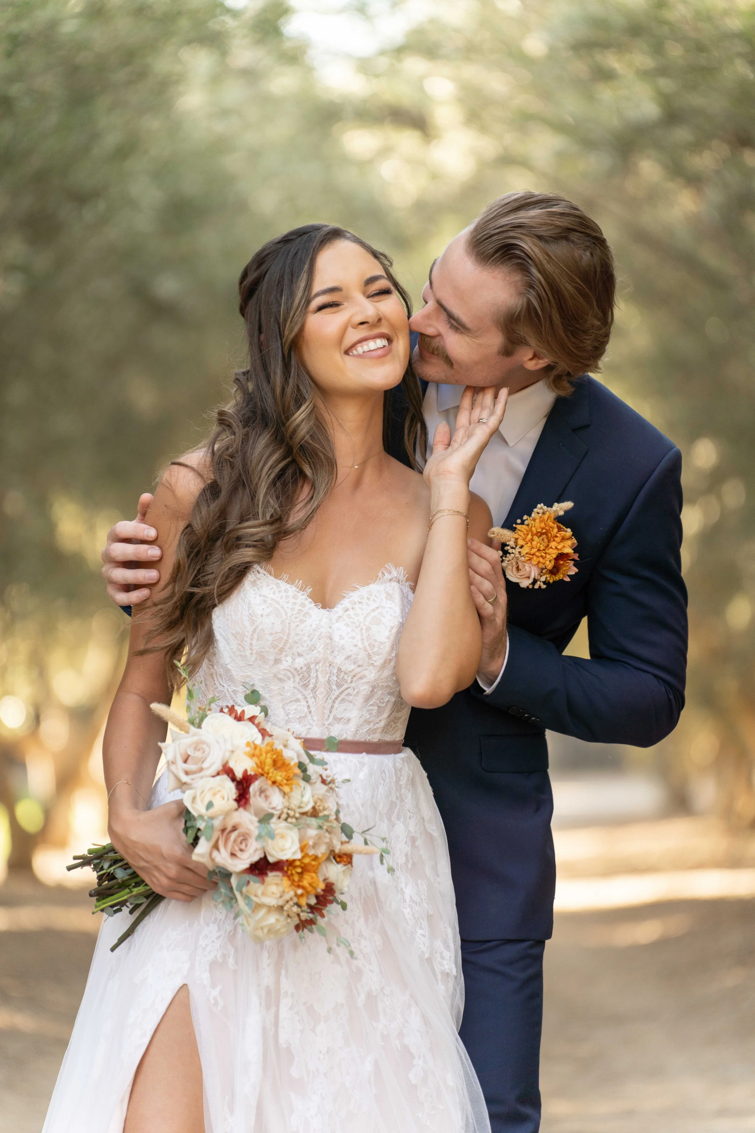 A newlywed couple sharing a joyful moment outdoors, with Georgia the bride holding a bouquet and the groom embracing her affectionately.