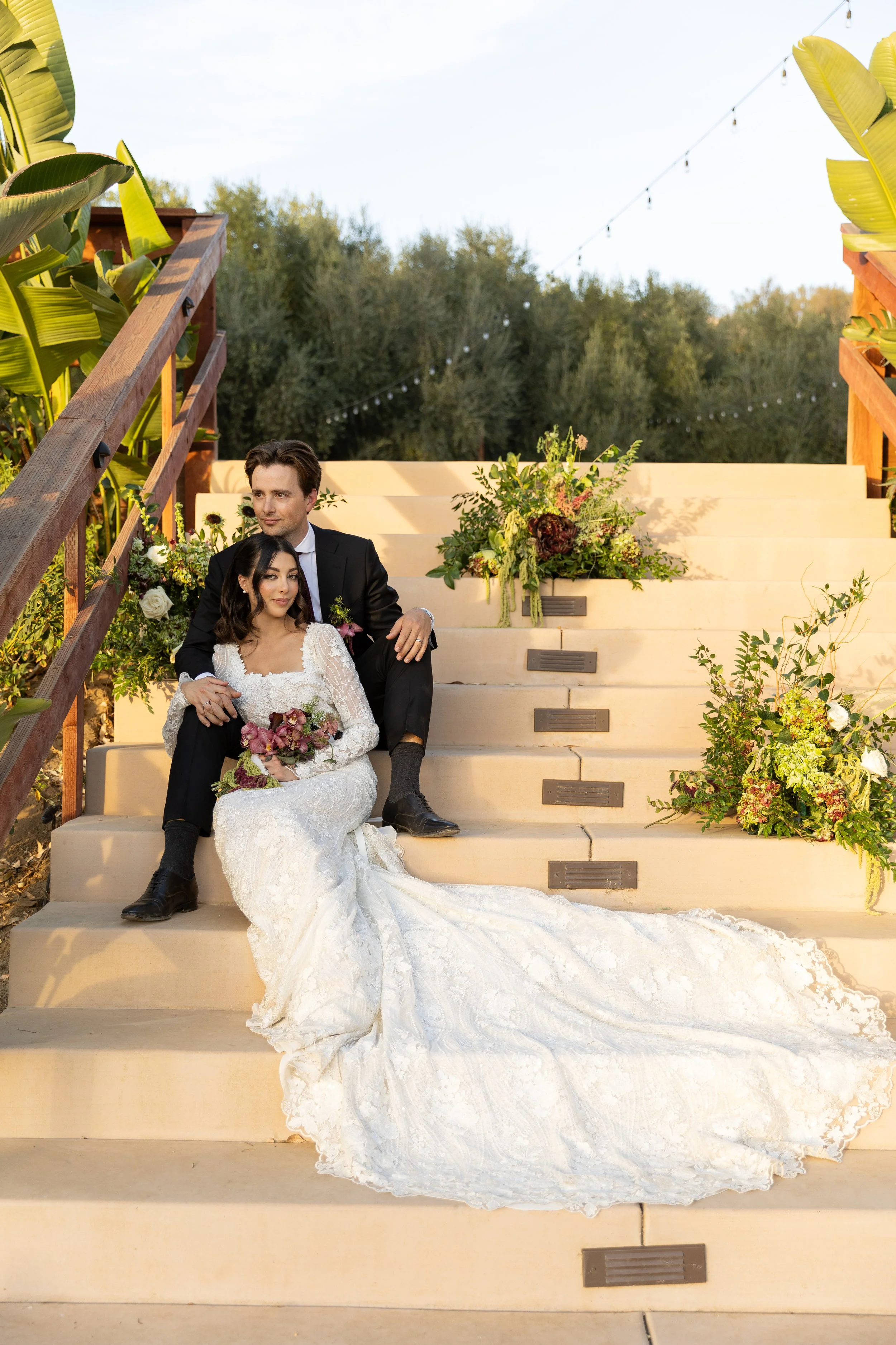 Newlyweds sit and pose on stairs at Monarca Ranch Wedding Venue