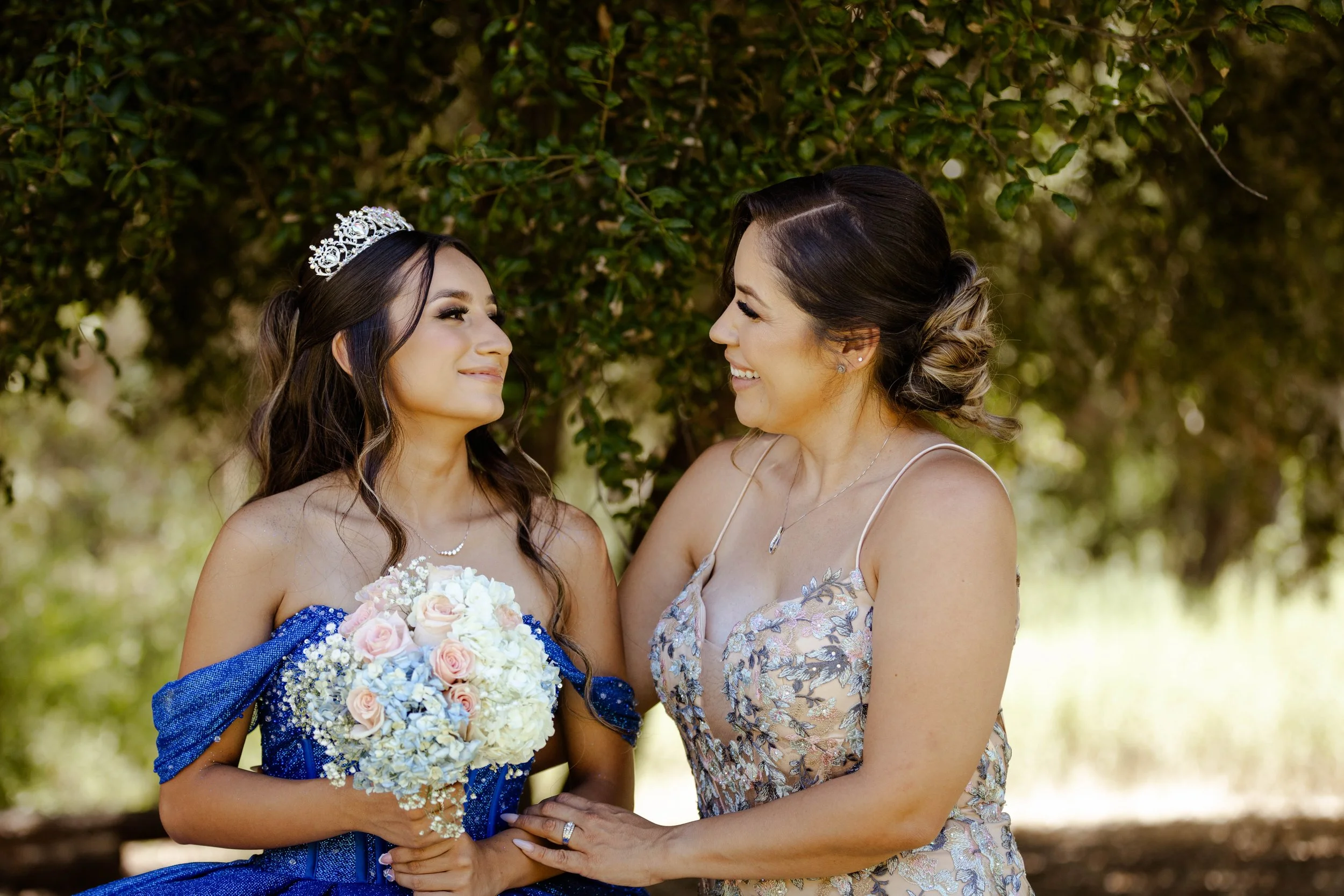 Mom and daughter smiling at each other with trees behind at Monarca Ranch CA