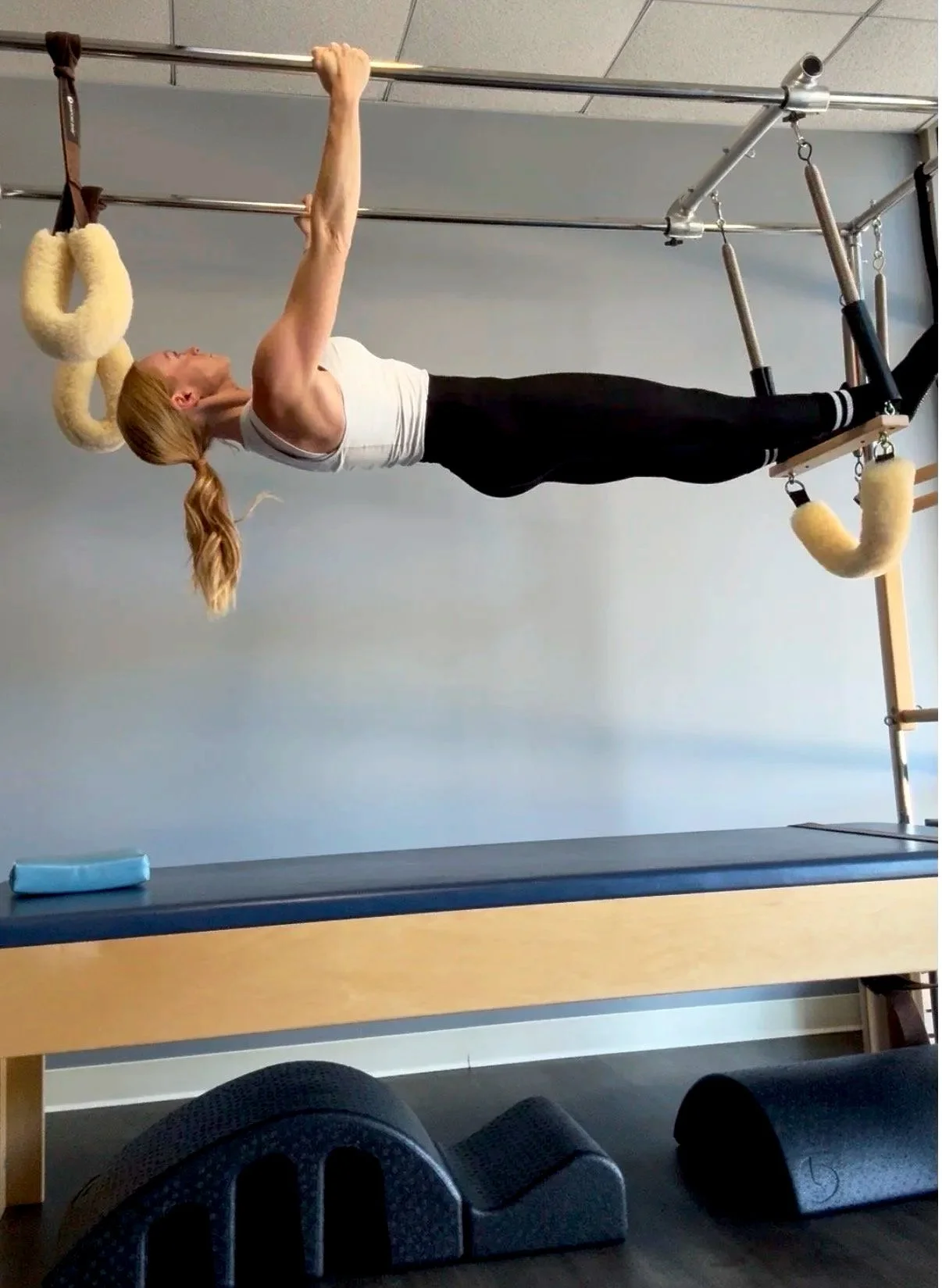 Woman practicing Pilates on Cadillac. Hanging pull-ups.