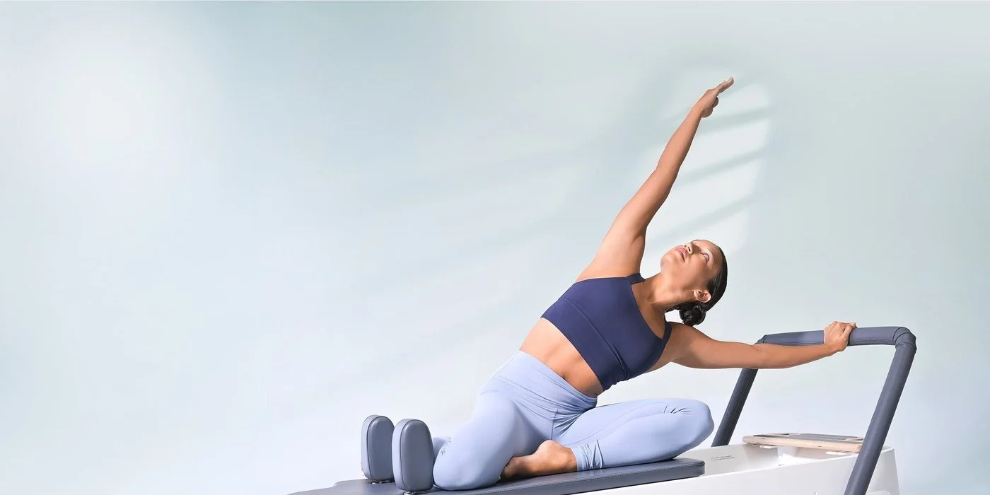 Woman performing a Mermaid stretch on a Balanced Body reformer