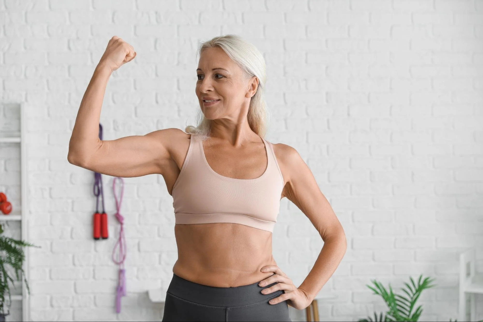 Strong older woman flexing her arm, symbolizing optimized aging through strength, hormones, and metabolic health--HealthSpan Internal Medicine in Boulder CO