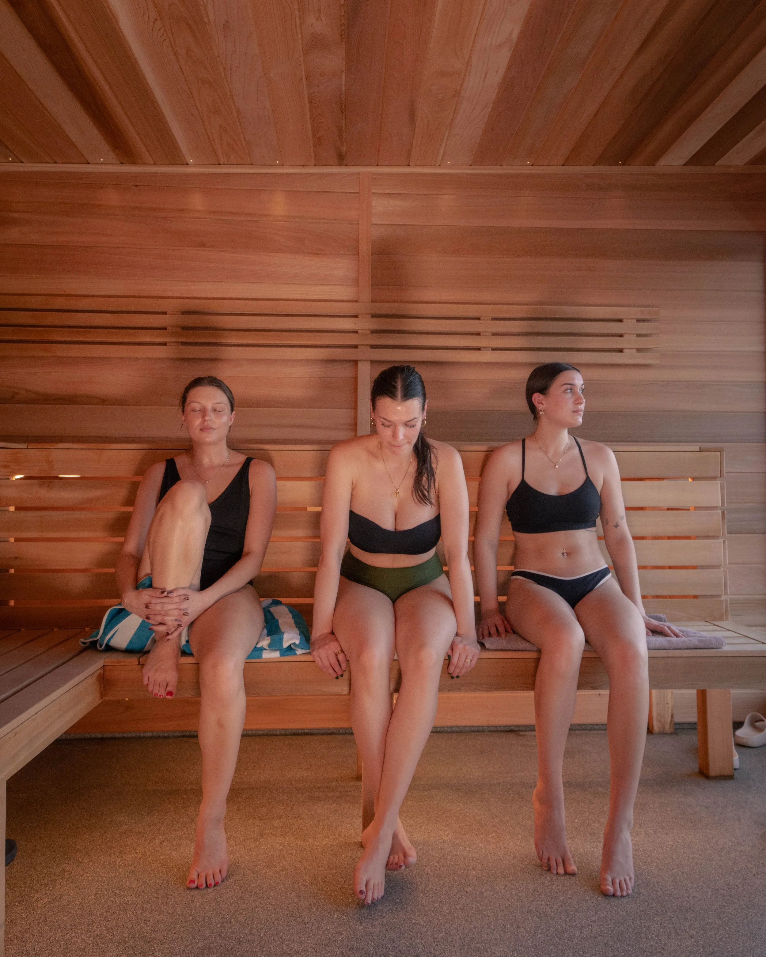 Three women sitting inside a wooden sauna, looking relaxed and rejuvenated.