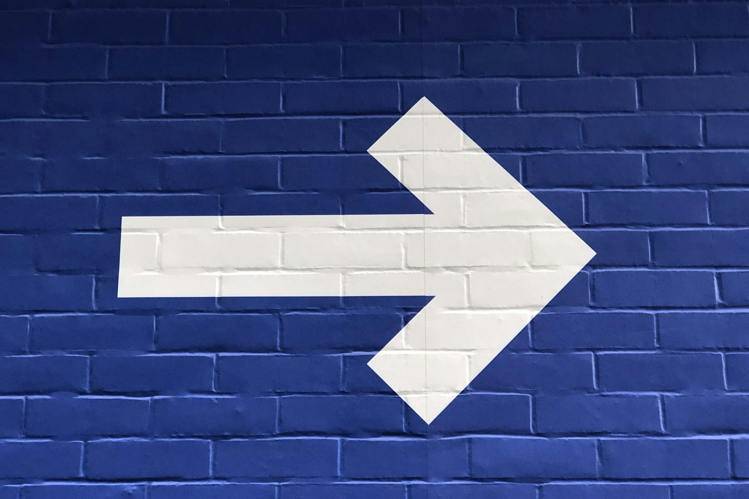 white arrow on a blue brick background