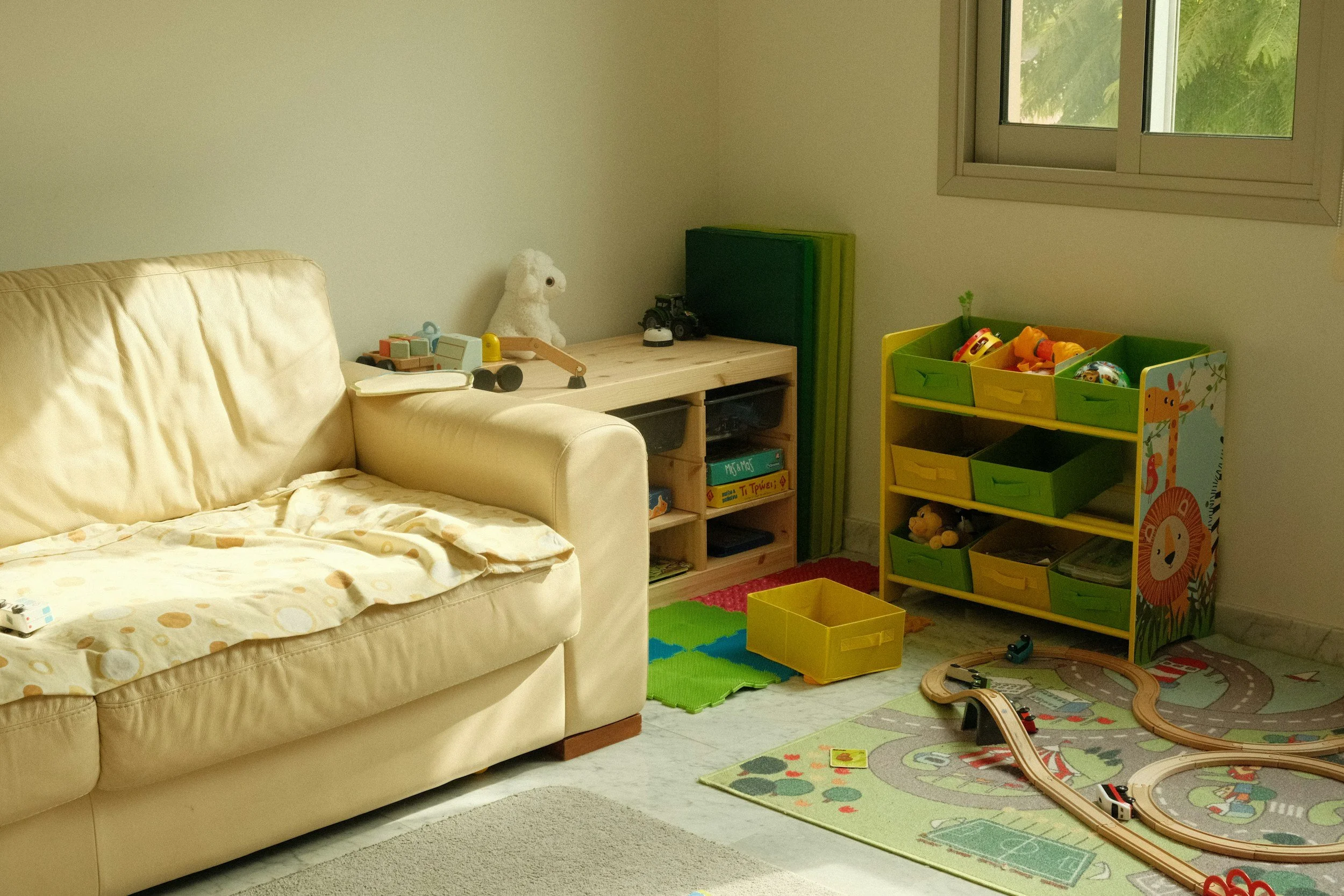 playroom with a yellow leather couch and train set