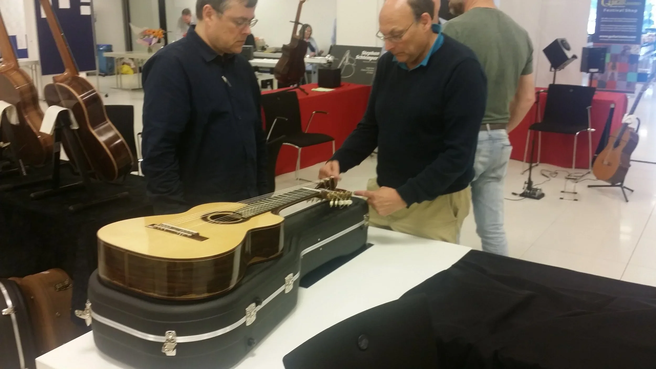 Two People looking at an eleven string guitar