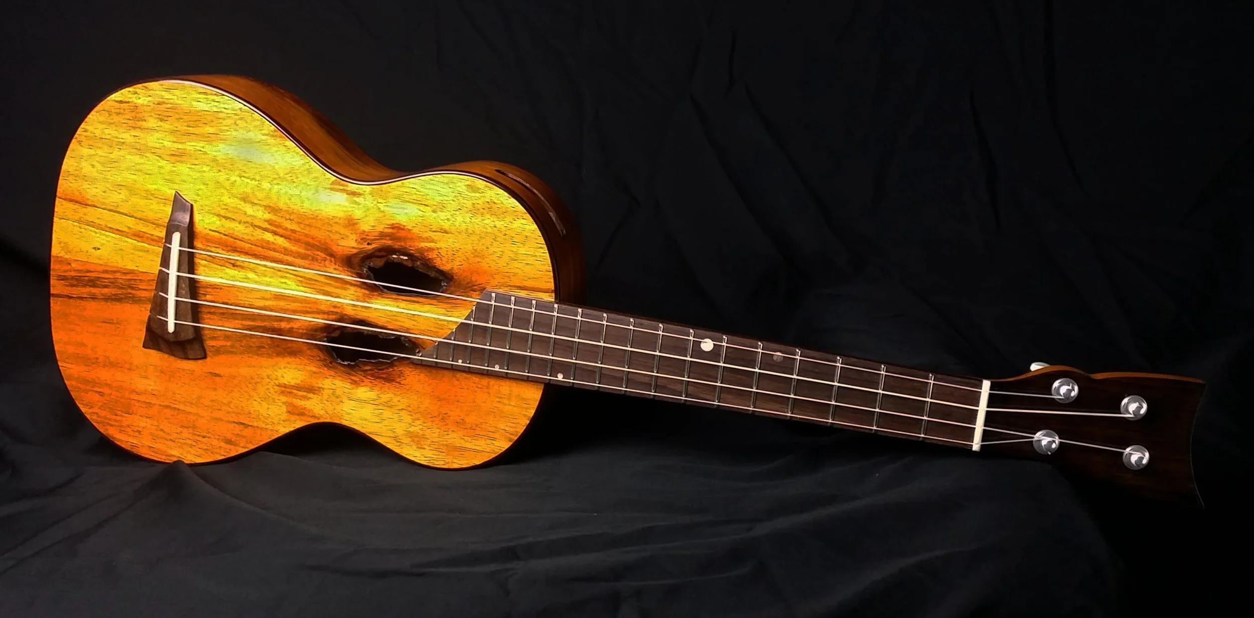 Ukulele with sound holes from wormholes in the wood. 