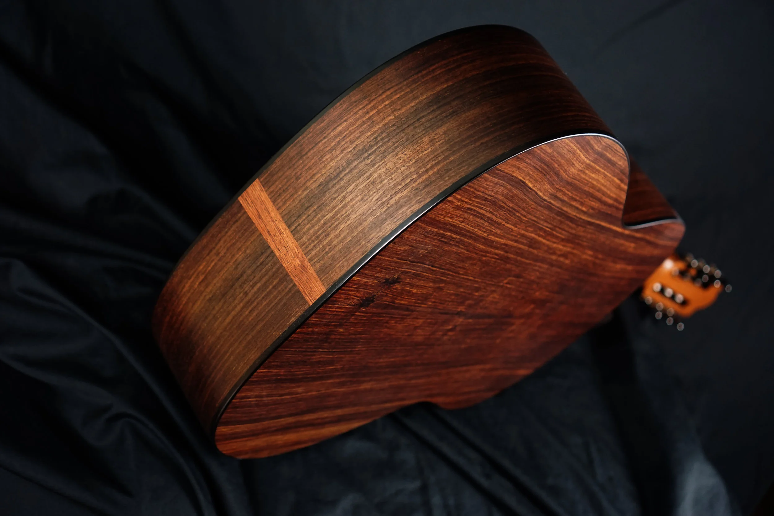 The back of an East Indian rosewood body classical guitar on a black background