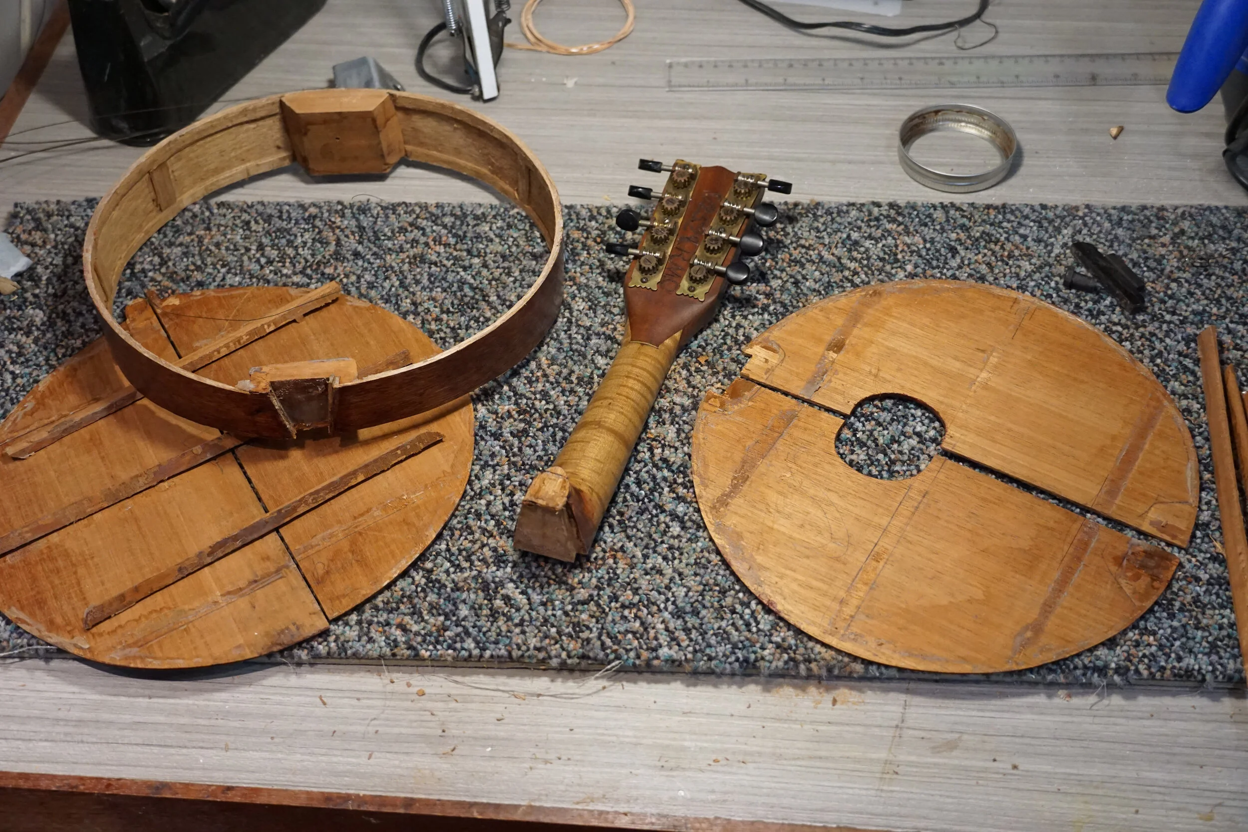 Parts of a homemade mandolin on a table to be restored.