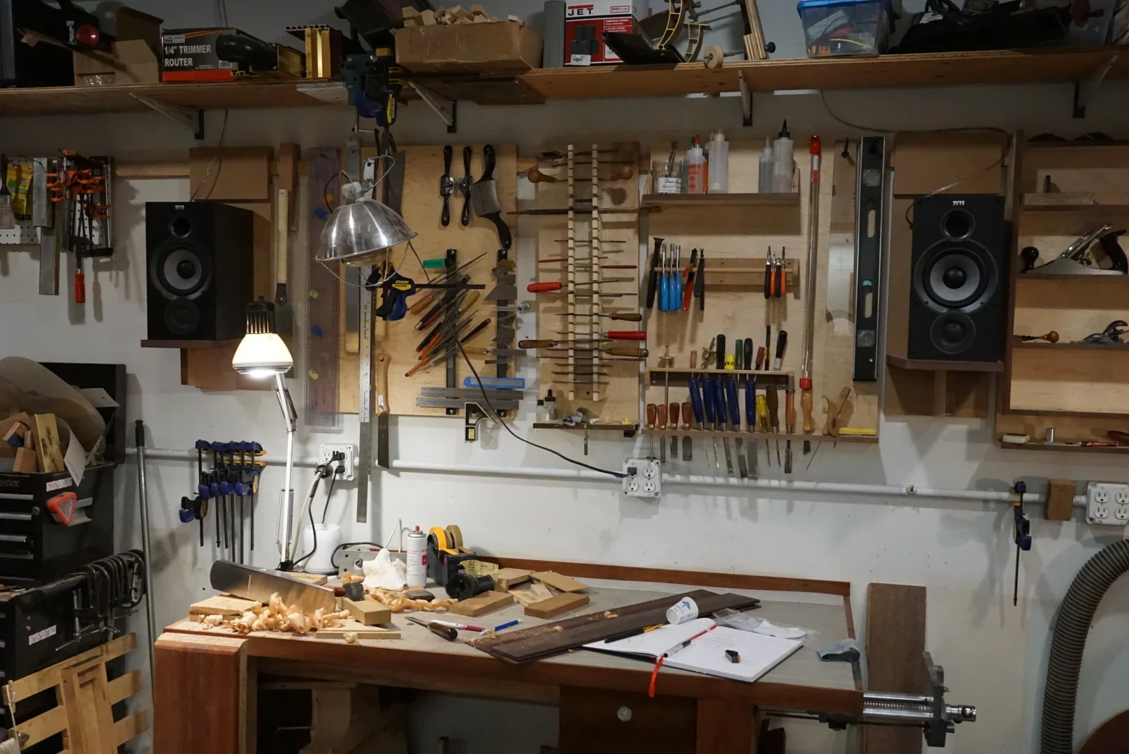 Luthier's bench with hand tools and speakers on the wall above.